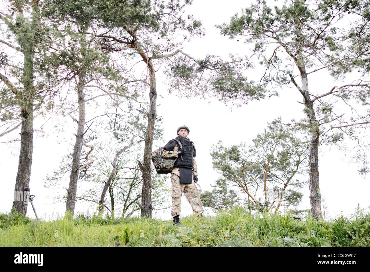 Ein junger Soldat in Uniformen und taktischer Weste arbeitet im Wald und bereitet sich auf die Aktion an einem temporären Waldstützpunkt vor. Ein Mann tut es bei der Minenräumung Stockfoto