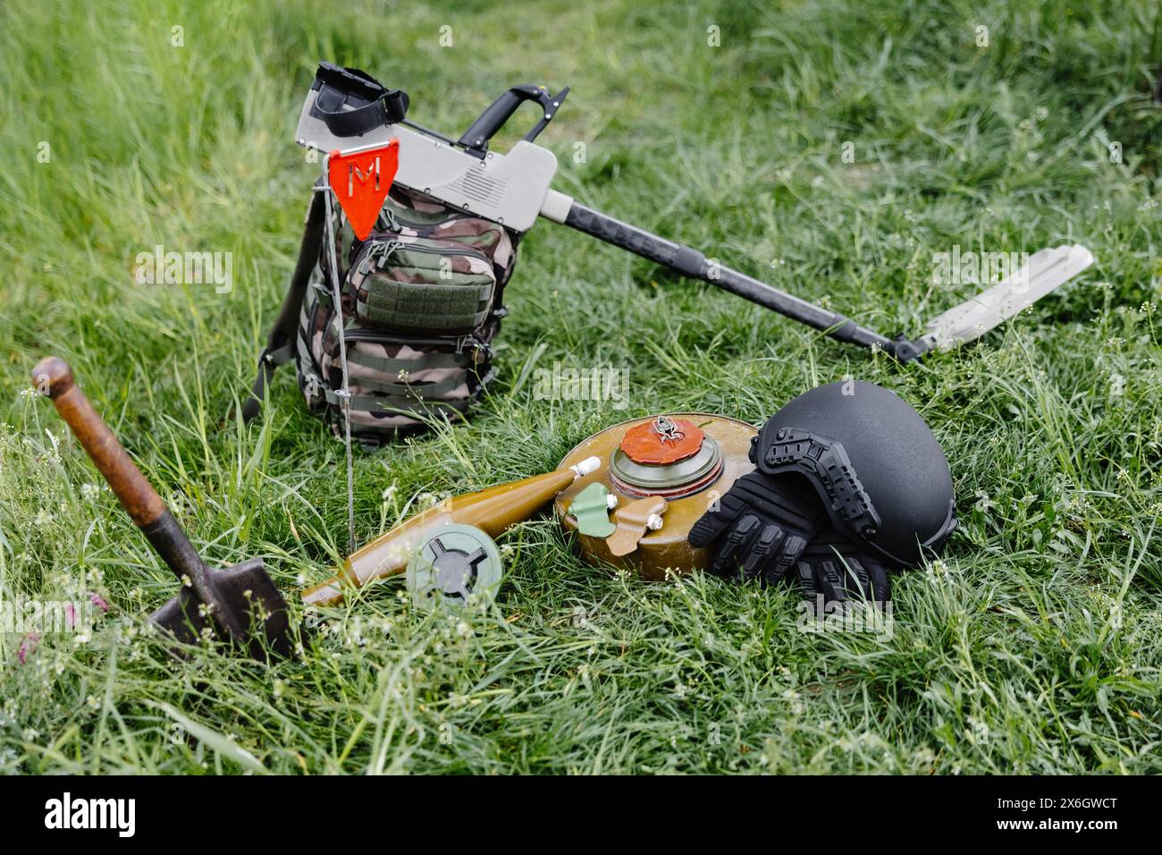 Sprengkörper und ein Metalldetektor liegen auf dem Hintergrund eines Waldmassivs. Ausrüstung für die Minenräumung des Gebiets. Stockfoto