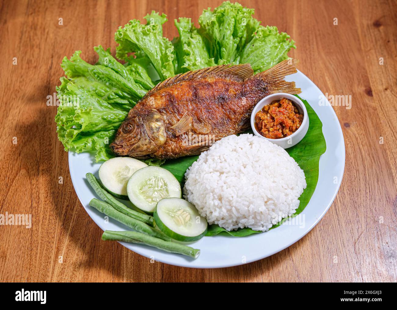 Frittierte Tilapia oder Ikan Nila Goreng serviert mit Salat, Gurke und Sambal auf Teller Stockfoto