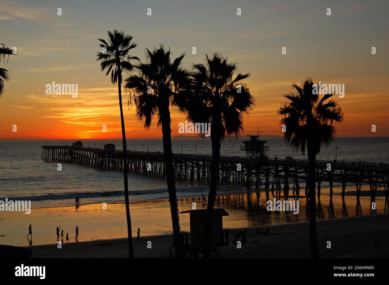 Am Ende des Tages bringt die untergehende Sonne am Strand die Palmen in Silhouette zum Himmel Stockfoto