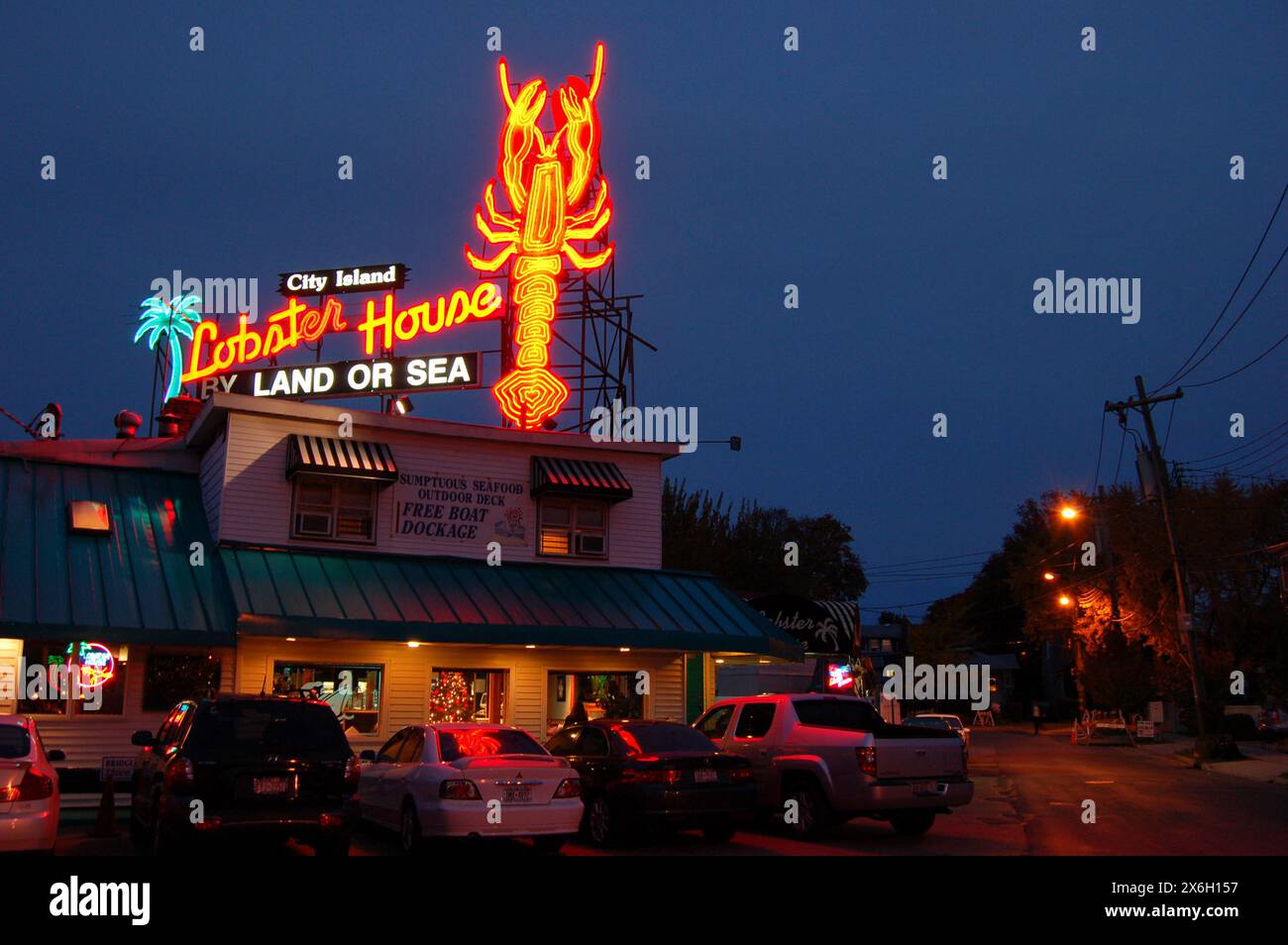 Ein großes Neonlicht-Schild wird nachts über einem Fischrestaurant und Café auf City Island, New York, beleuchtet Stockfoto