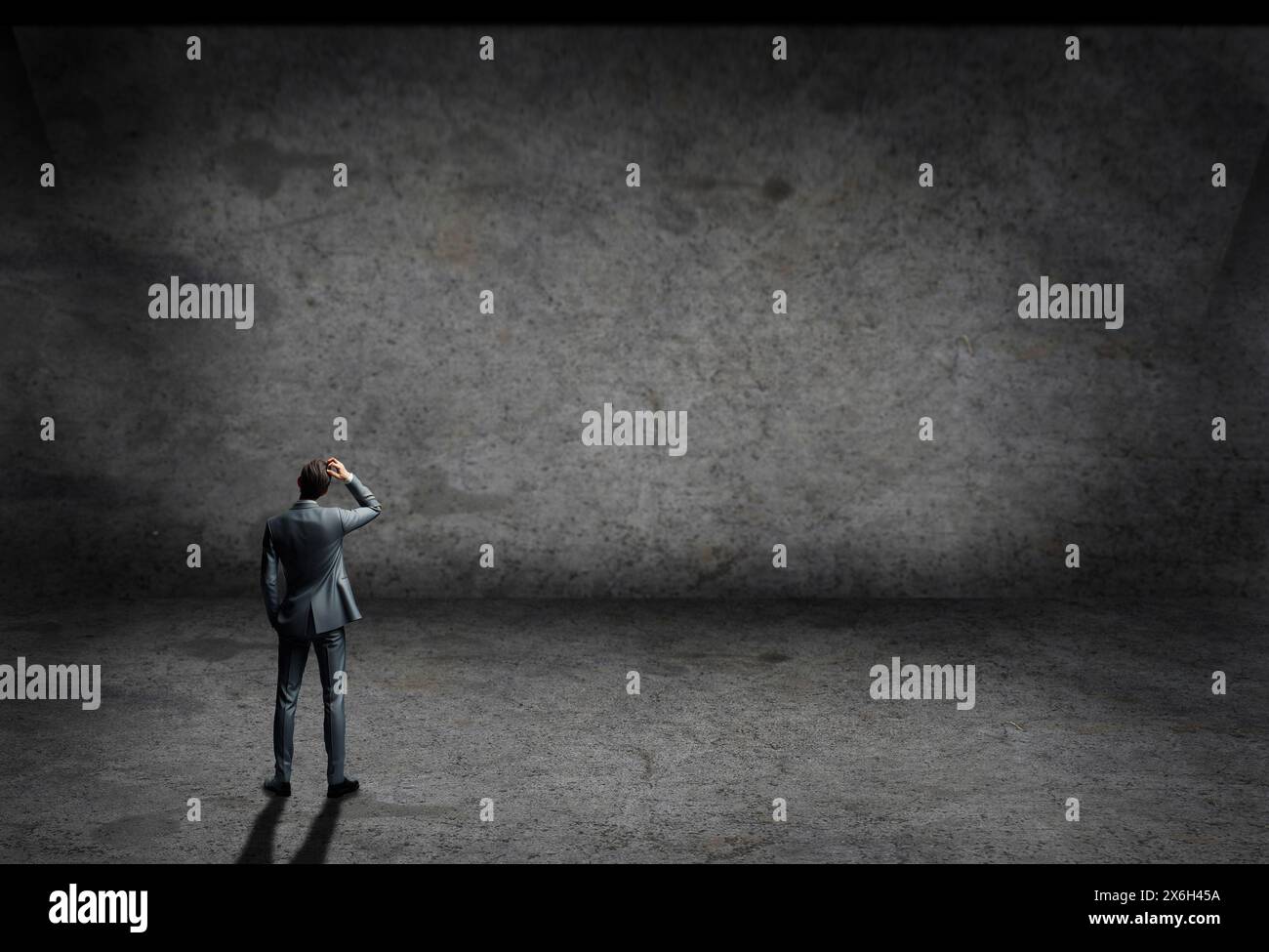 Mann im Anzug in einem leeren Raum mit grauen Wänden und Boden aus Beton Stockfoto