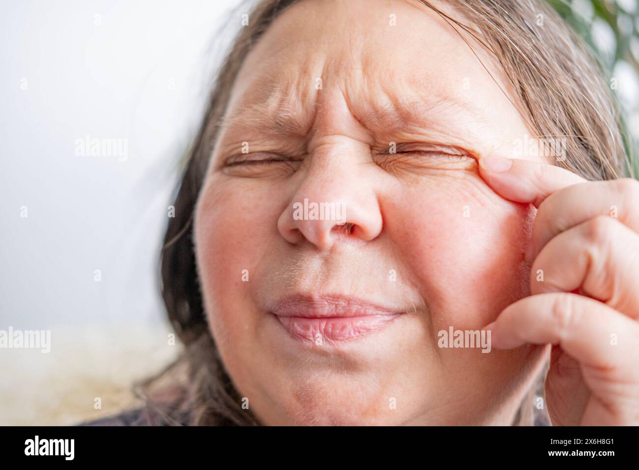 kaukasische reife Frau mit schmerzhaftem Auge, Staubpickel in das Auge der Frau, verursacht Unannehmlichkeiten und Irritationen, Augengesundheit, Sehstörungen Stockfoto