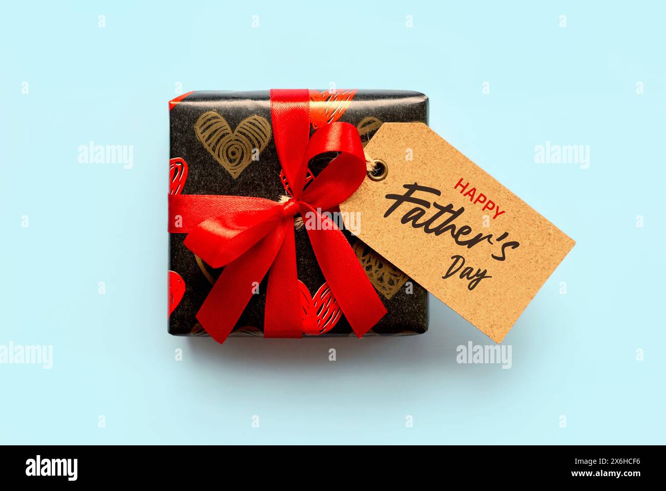 Alles Gute zum Vatertag. Draufsicht der Geschenkbox mit roter Schleife und braunem Verkaufsanhänger mit dem Text Happy Vatertag auf blauem Hintergrund Stockfoto