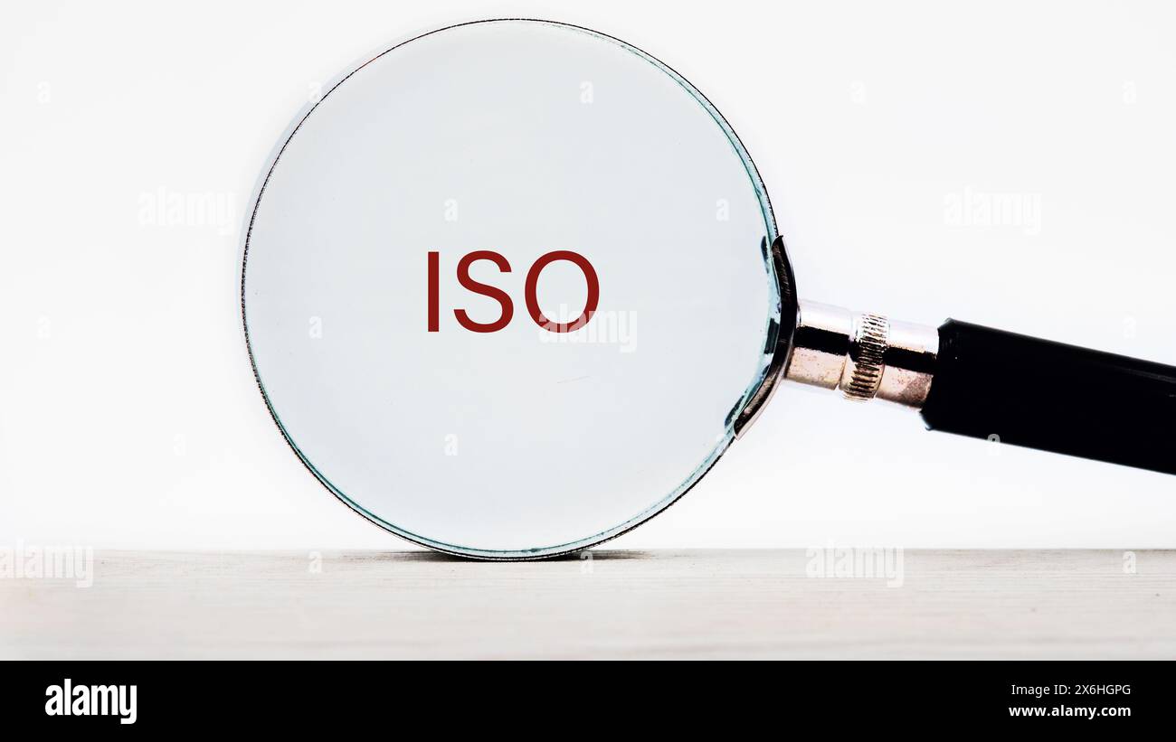 Das Konzept der ISO-Qualitätskontrollzertifizierung. Die Abkürzung ISO Text erscheint durch eine Lupe auf weißem Hintergrund Stockfoto