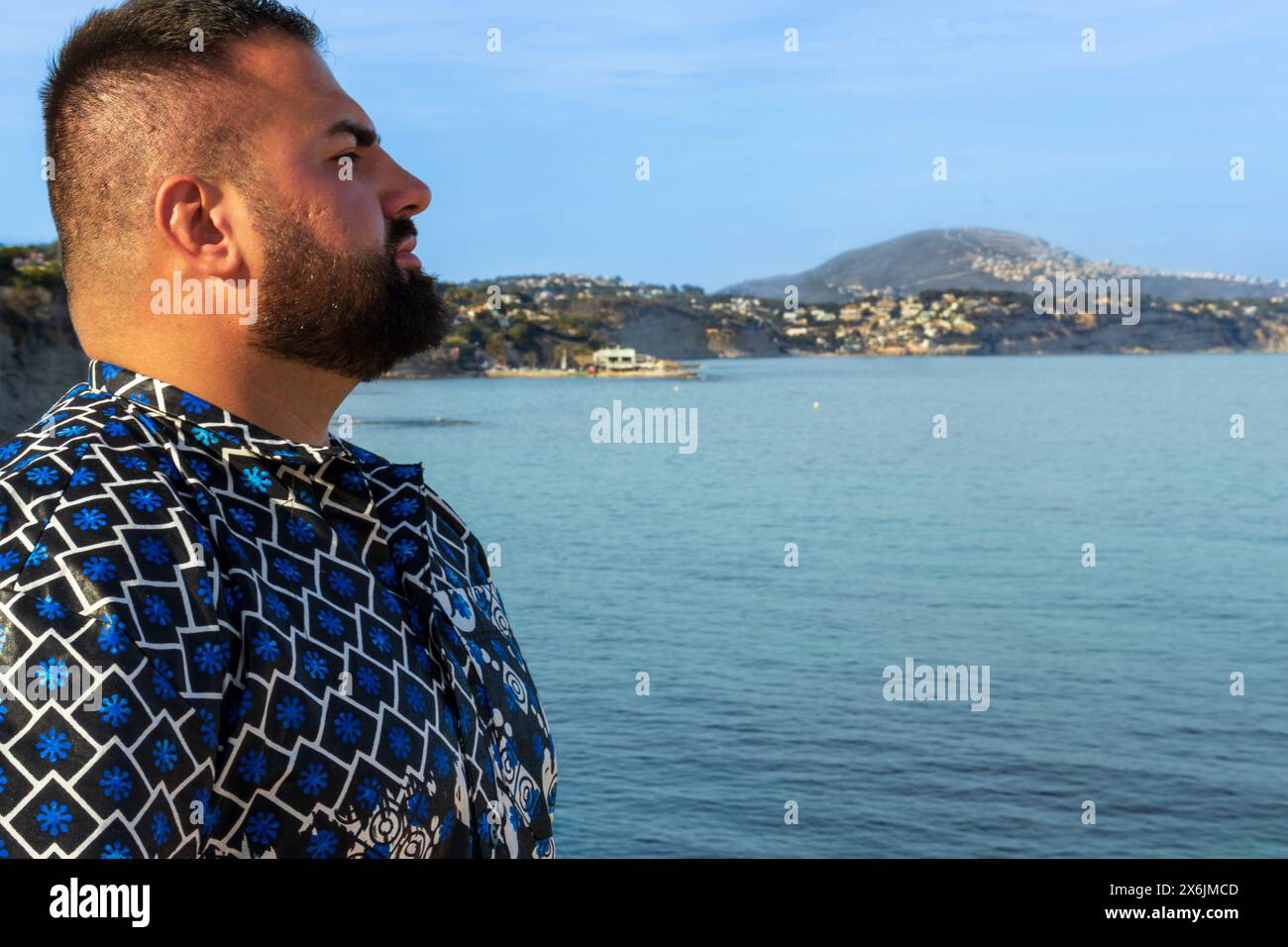 Dieses Porträt fängt einen 30-jährigen Mann ein, der am Meer steht, und sein Blick reflektiert ein Gefühl der Ruhe und der Introspektion. Stockfoto