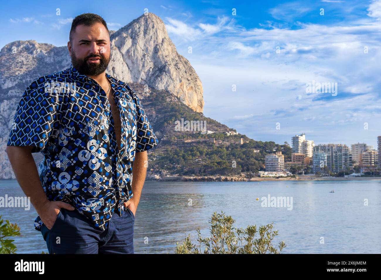 Dieses Porträt zeigt einen 30-jährigen Mann in Calpe, Spanien, während er in der Betrachtung vor dem herrlichen Ifach-Felsen steht. Stockfoto