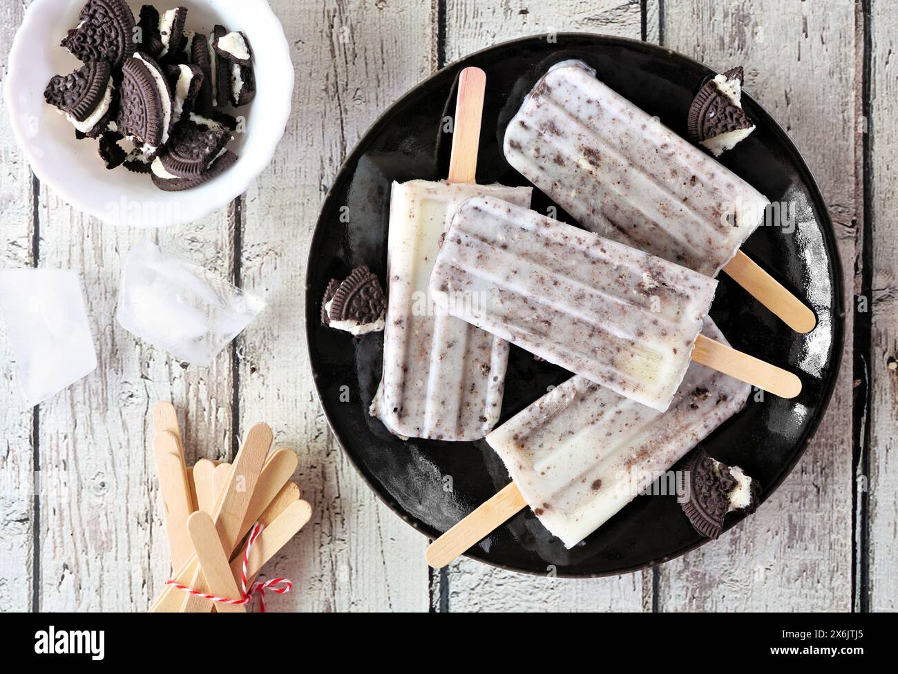 Kekse und Creme-Eis auf einem schwarzen Teller. Draufsicht über einem weißen Holzhintergrund. Stockfoto