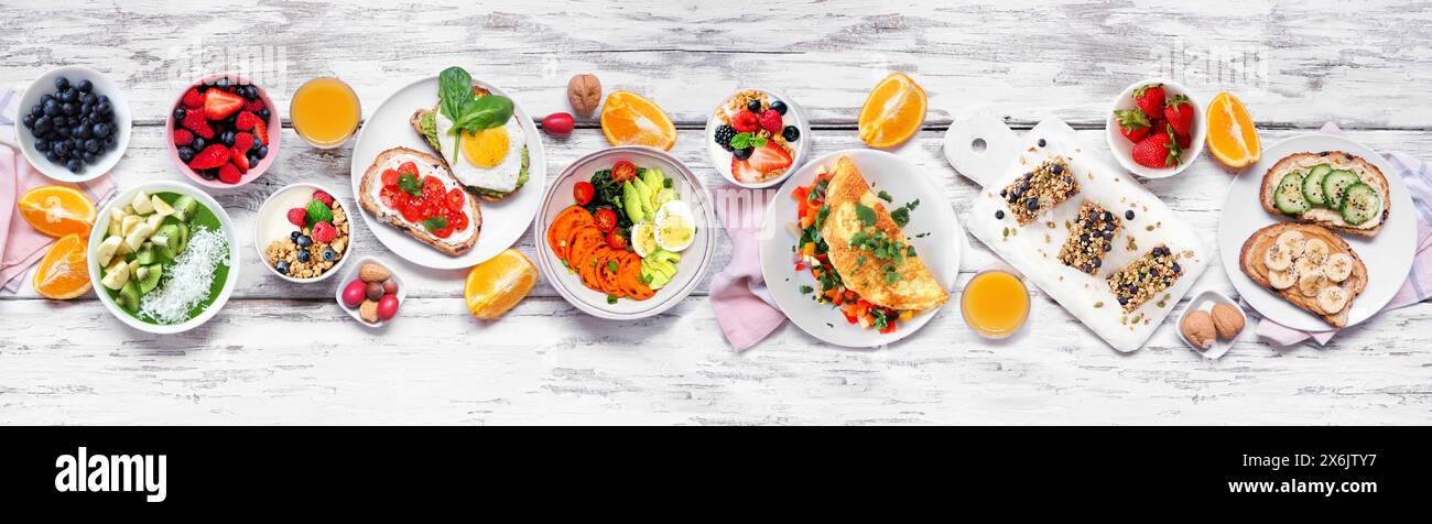 Gesunde Frühstücks-Food-Tischszene. Ansicht von oben nach unten über einem weißen Holzbanner Hintergrund. Omelette, nahrhafte Schüssel, Toasts, Müsliriegel, Smoothie Schüssel, Stockfoto