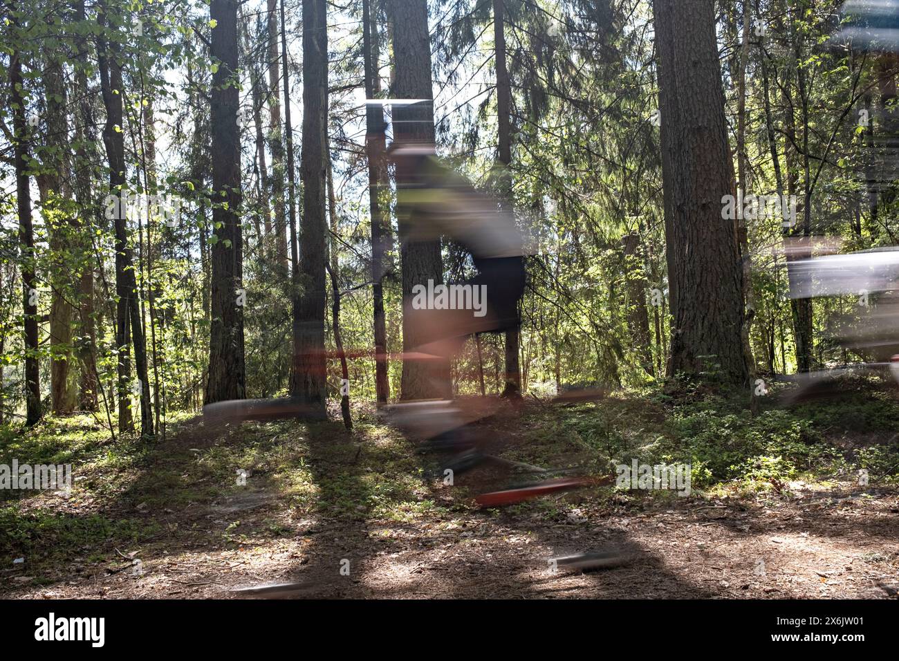 Verschwommenes Bild eines Mannes auf dem Mountainbike auf der Forststraße während des MTB-Radmarathons in Sigulda, Gauja-Nationalpark, Lettland am 12. Mai 2024 Stockfoto