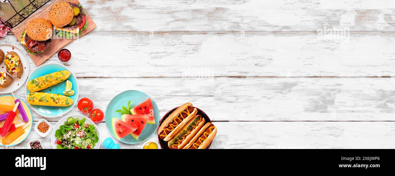 Barbecue-Küche im Sommer an der Grenze. Hamburger, Hot Dogs, Kartoffeln, Mais und kalte Leckereien. Über dem Hintergrund eines weißen Holzbanner. Kopierbereich. Stockfoto