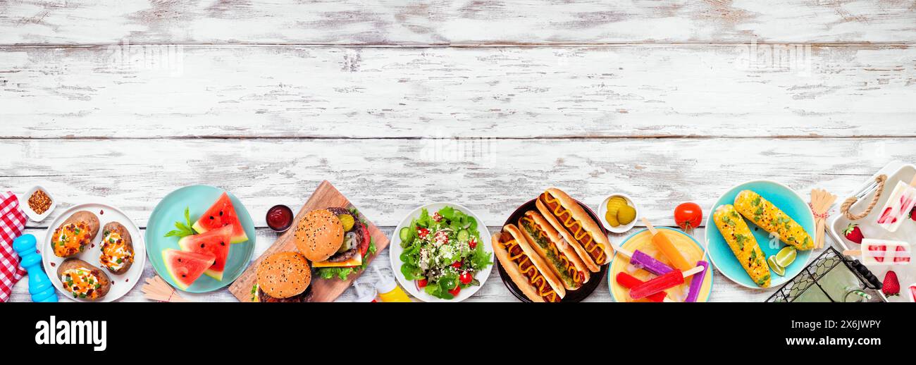 Sommer BBQ Food unten Rand. Hamburger, Hot Dogs, Kartoffeln, Mais und kalte Leckereien. Ansicht von oben nach unten über einem weißen Holzbanner Hintergrund. Kopierbereich. Stockfoto