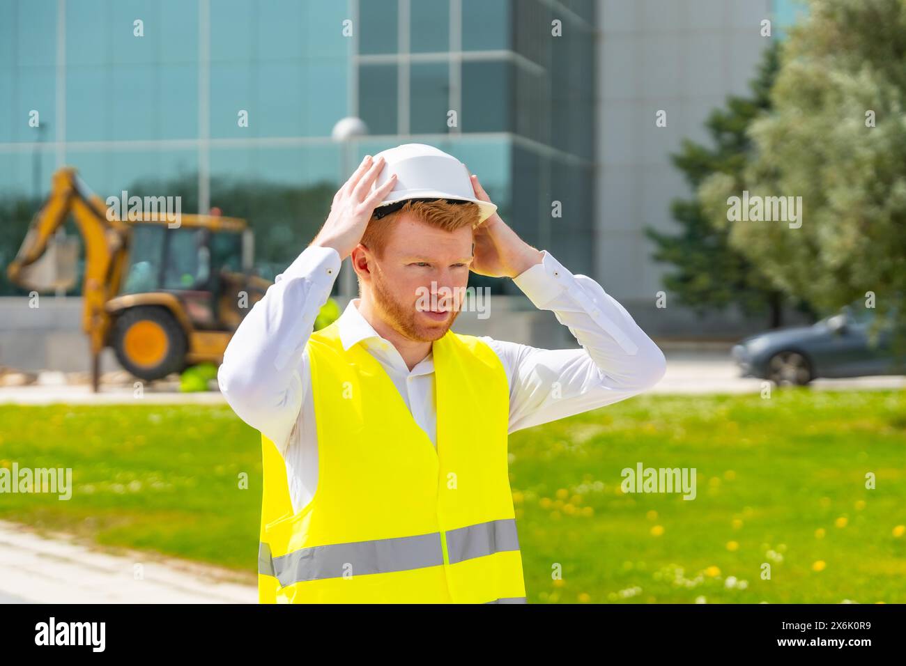 Architekt mit reflektierender Weste, die ihren Schutzhelm auf einer Baustelle anpasst Stockfoto
