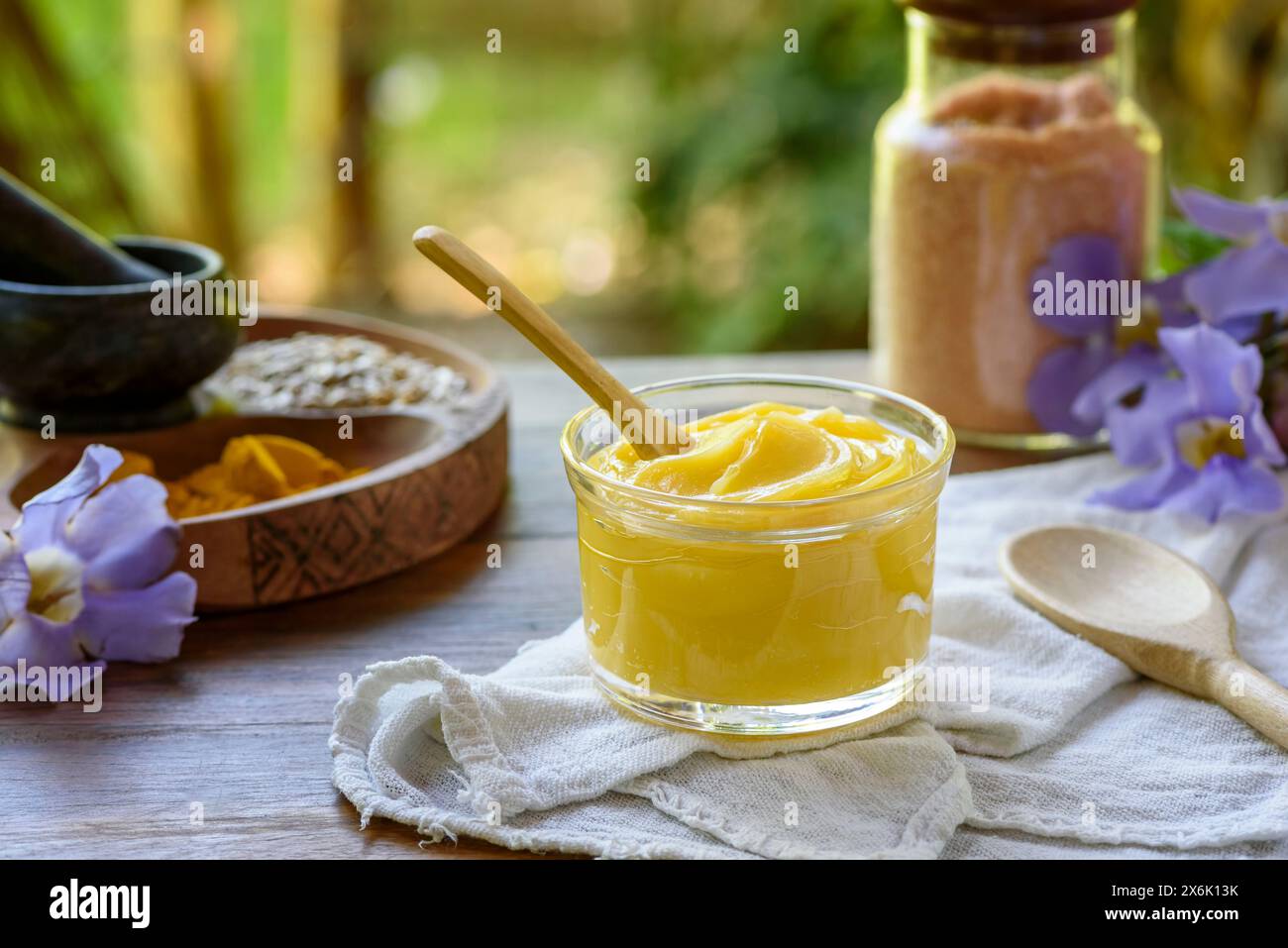Ghee-Butter im Glas mit Holzlöffel auf Holztisch mit verschwommenem Hintergrund. Stockfoto