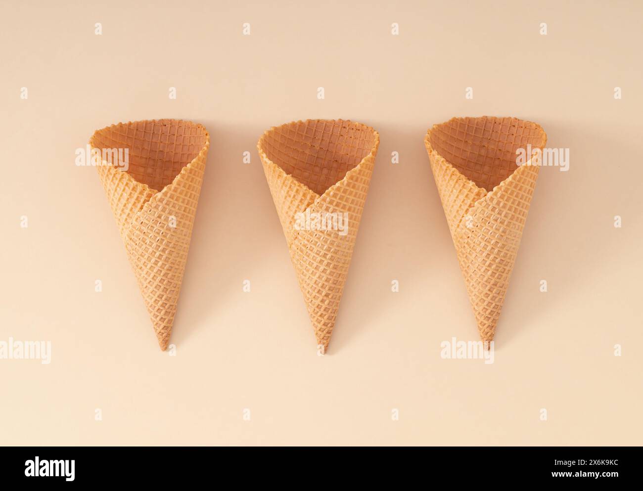 Eiskegel auf Pastell-Creme-Hintergrund. Kreatives Sommerkonzept. Minimales Design. Sommerkost-Ästhetik. Flache Lagen. Stockfoto