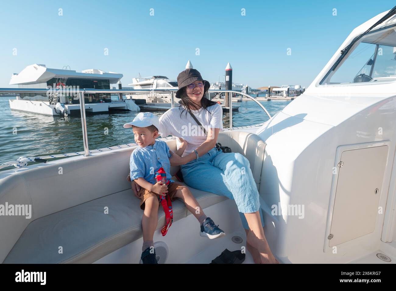 Ein kleiner Junge macht eine Bootsfahrt mit seiner Mutter am Al Bandar Marina in der Nähe von Yas Island, mit der Skyline von Abu Dhabi im Hintergrund könnte es sich um ein Asien handeln Stockfoto
