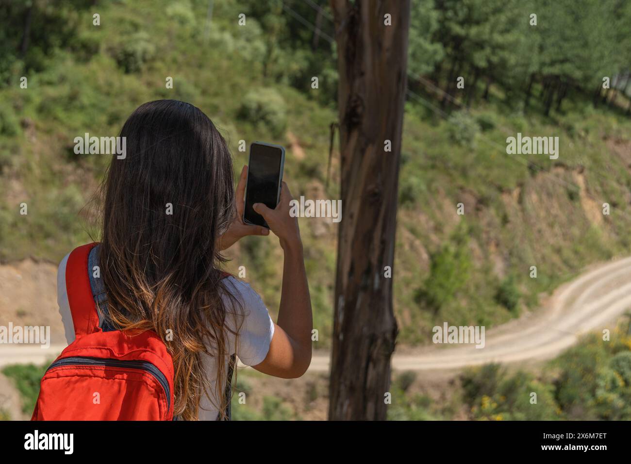 Eine Reisende, die mit ihrem Handy ein Foto von der Landschaft macht, nachdem sie über den Berg gewandert ist. Stockfoto