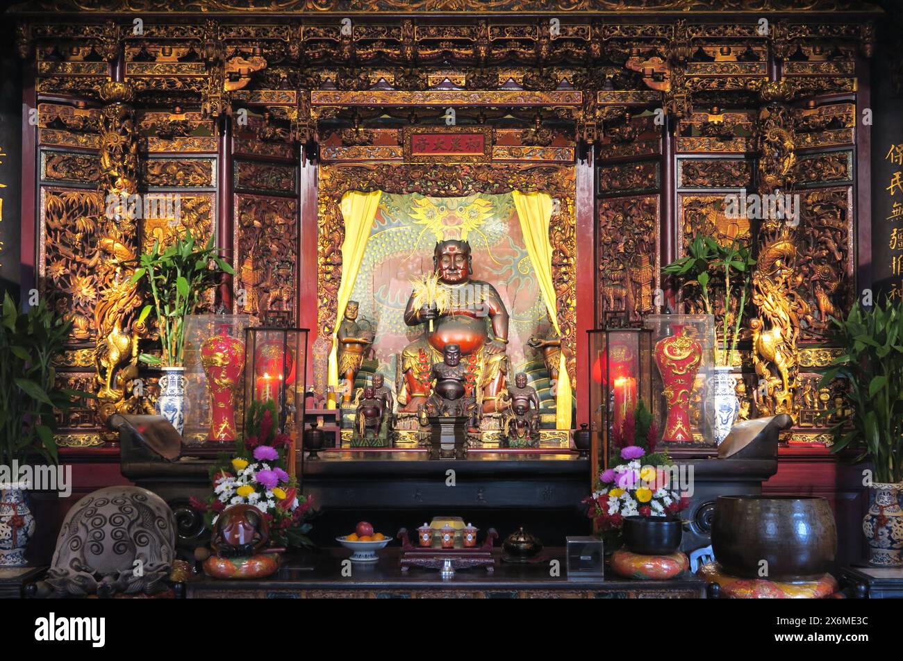 Ein kunstvoller Altar mit Blumenschmuck und Opfergaben, Statue des legendären Proto-Kaisers Shennong („göttlicher landmann“) in Dalongdong Baoan Stockfoto