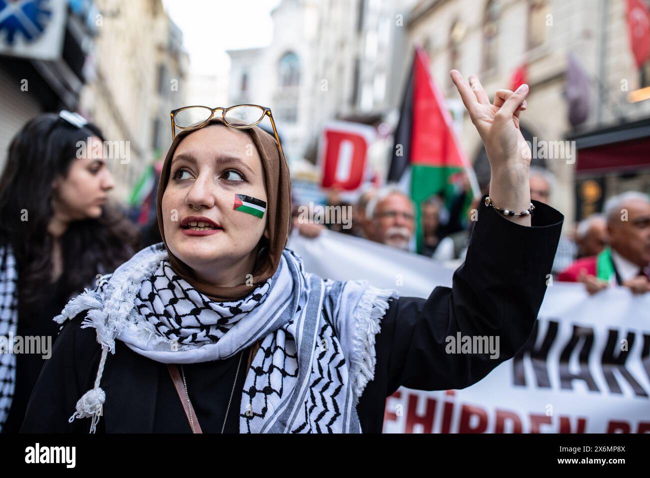 Istanbul, Türkei. Mai 2024. Eine weibliche Demonstrantin, die einen Aufkleber mit palästinensischer Flagge auf ihrem Gesicht hatte, machte ein Siegeszeichen und sang Slogans, während sie ging. Menschen versammeln sich, um gegen israelische Angriffe auf Gaza zu protestieren und um den 76. Jahrestag des Nakba-Tages in Istanbul, Türkei, zu feiern. In Eminonu fand anlässlich des Nakba-Tages ein Gedenkprotest statt. Demonstranten versammelten sich vor dem großen Postamt (PTT) in Sirkeci und marschierten zum Eminonu-Platz. Quelle: SOPA Images Limited/Alamy Live News Stockfoto