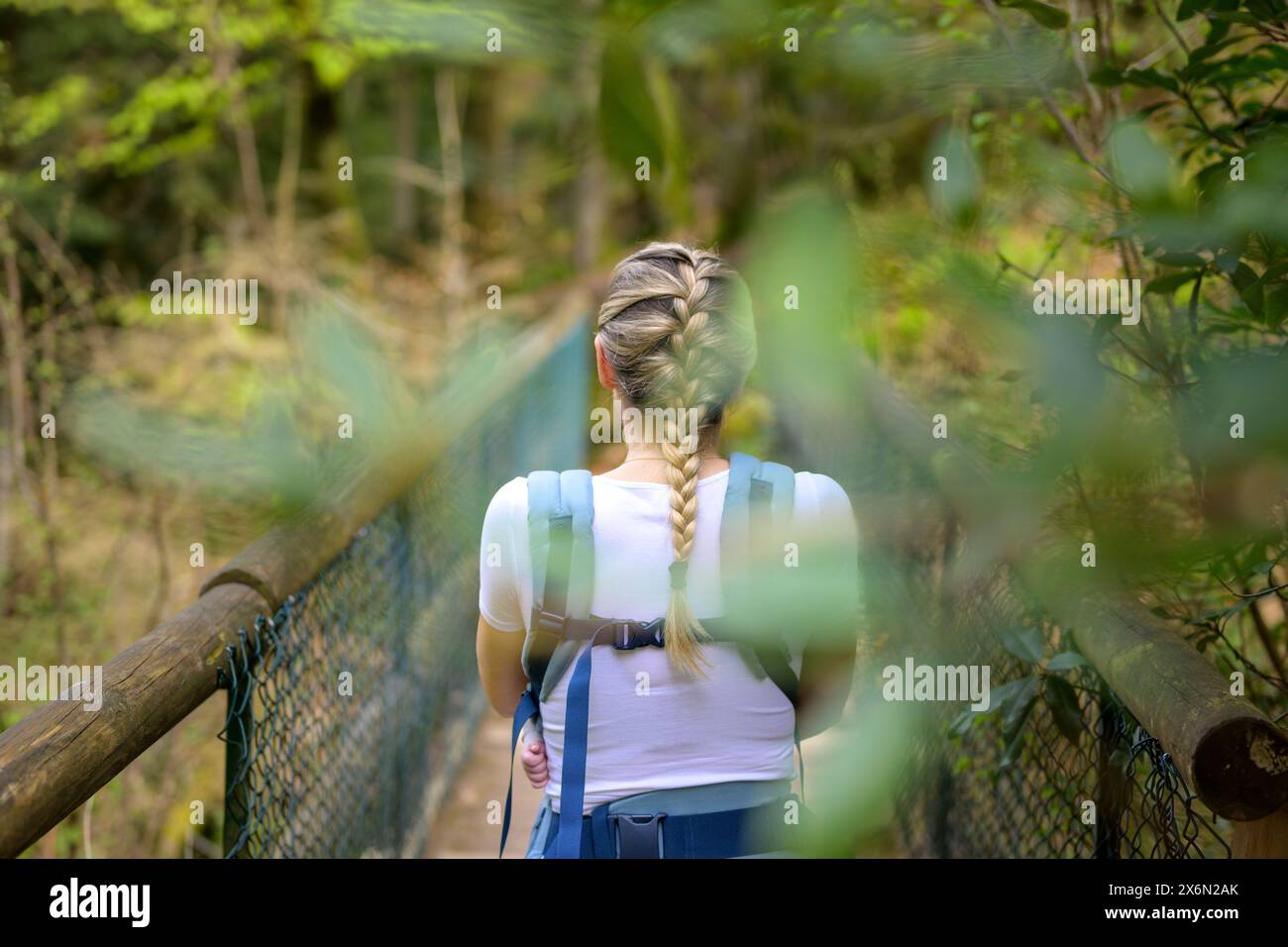 Rückansicht einer blonden Frau, die mit ihrem kleinen Baby auf einer Brücke in der Natur steht Stockfoto