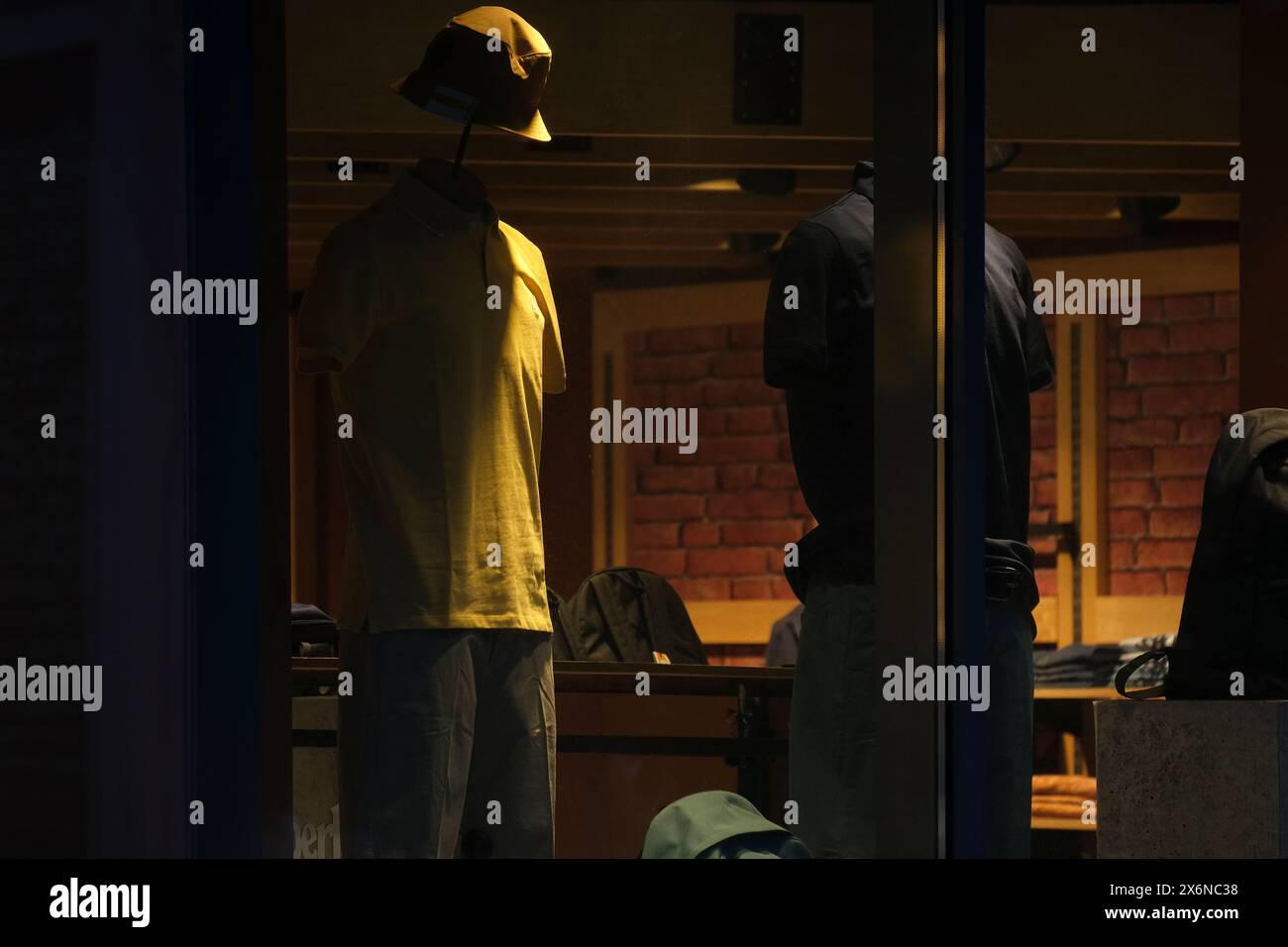 Schaufenster mit Schaufensterpuppen in lässiger Kleidung, beleuchtet durch warme Innenbeleuchtung, schaffen eine gemütliche und einladende Atmosphäre Stockfoto