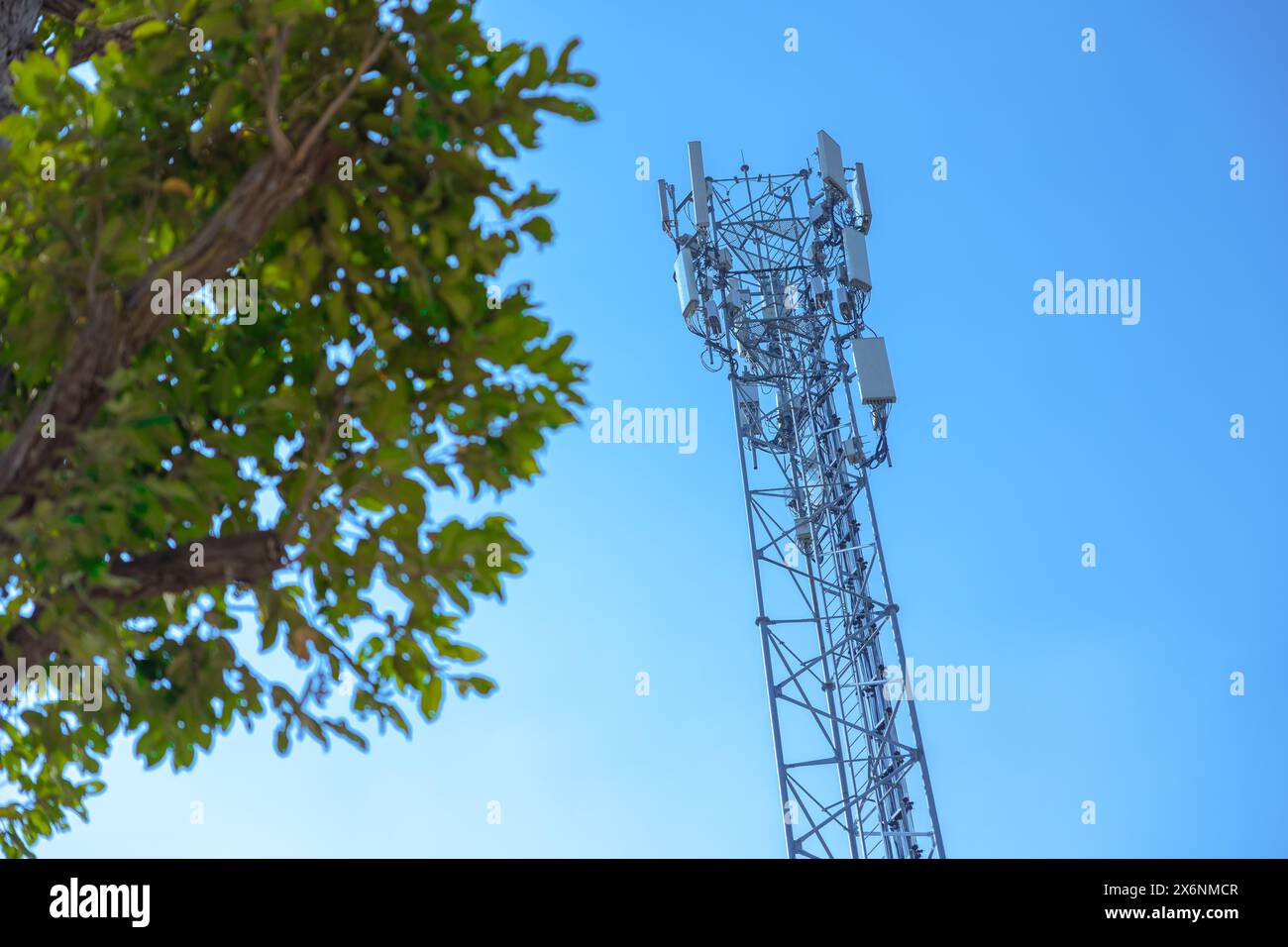 Außenbereich 5g-Kommunikationsturm digitales drahtloses Funksignal Fernübertragungszelle am blauen Himmel mit grünem Baum Stockfoto