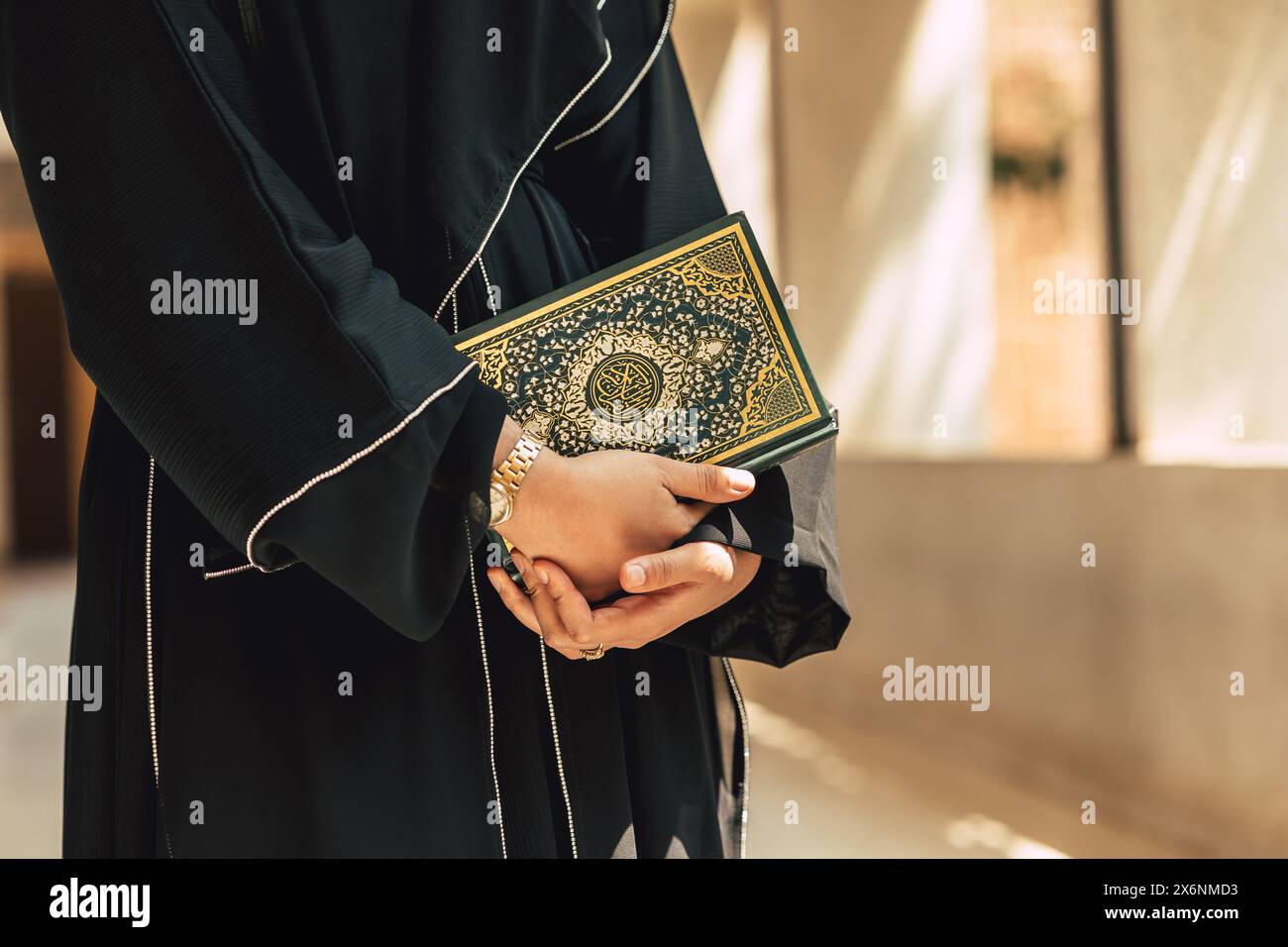 Heiliger Koranbucheinband mit arabischer Kalligraphie übersetzen die Bedeutung des Al-Koran. Die Hand der Araber hält ein muslimisches Koran-Buch. Stockfoto