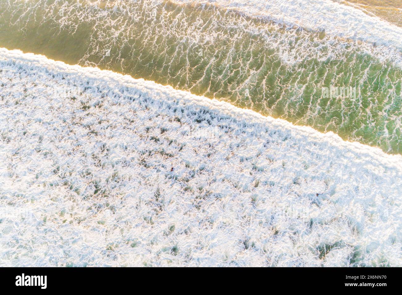 Aus der Vogelperspektive mit Drohne auf die schäumenden Wellen am Ufer eines Strandes bei Ebbe. Bild-Konzept für den Sommer Stockfoto