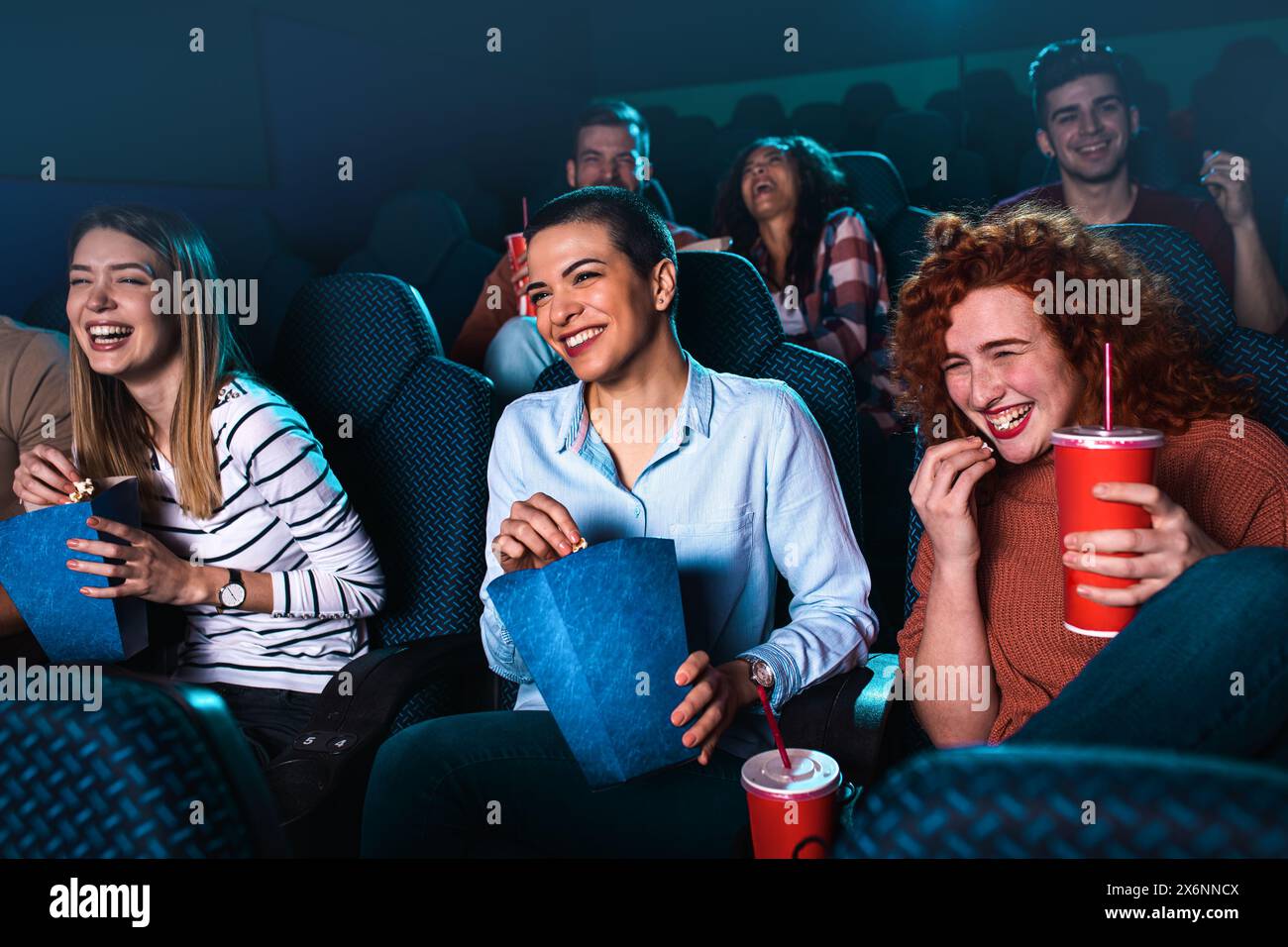 Eine Gruppe fröhlicher Leute lacht, während sie im Kino Filme anschauen. Stockfoto