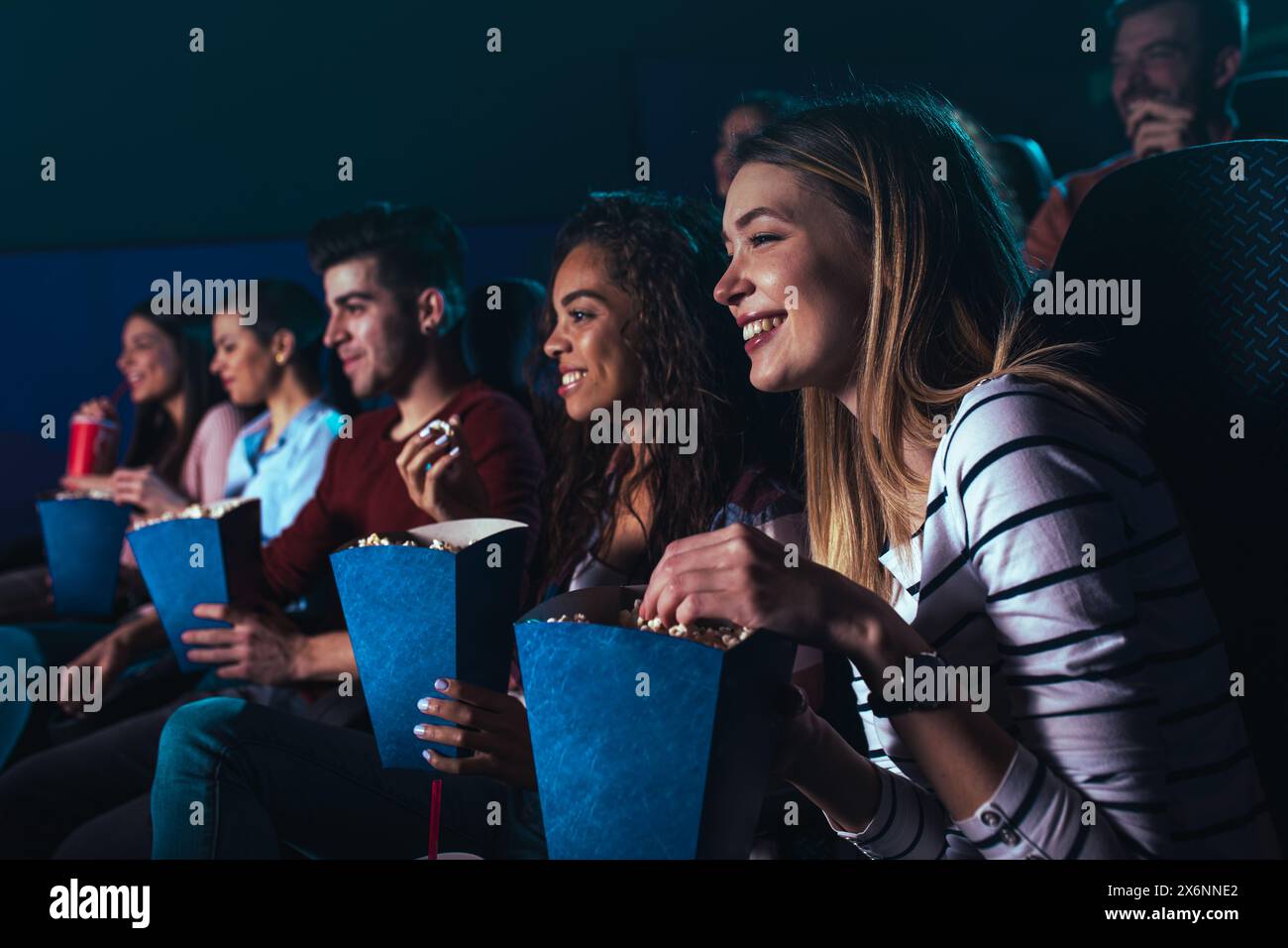 Eine Gruppe fröhlicher Leute lacht, während sie im Kino Filme anschauen. Stockfoto