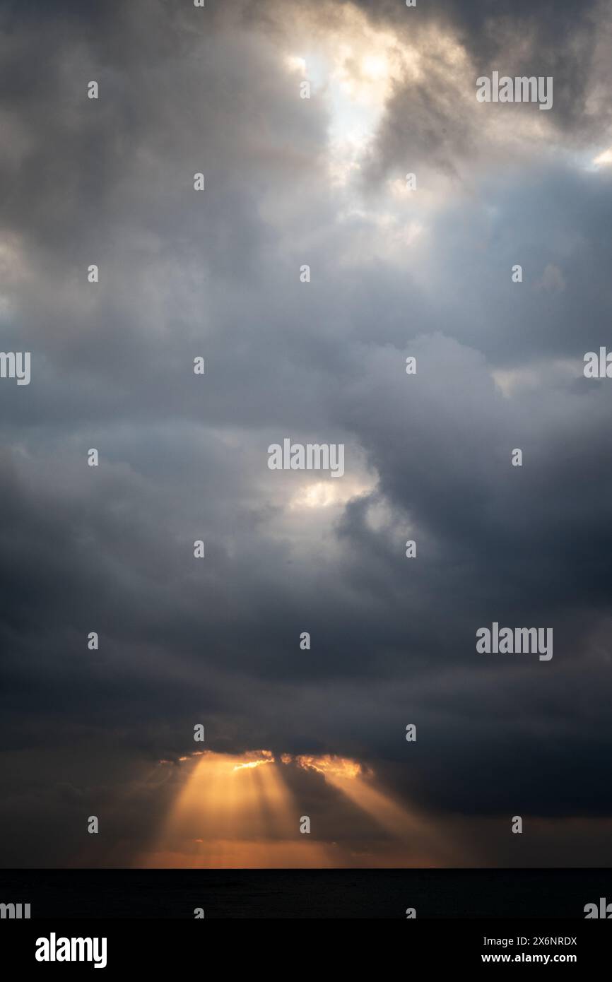 Goldene Sonnenstrahlen schießen bei Sonnenaufgang über dem Mittelmeer vor der Küste von Malaga, Südspanien, durch die Wolken. Stockfoto