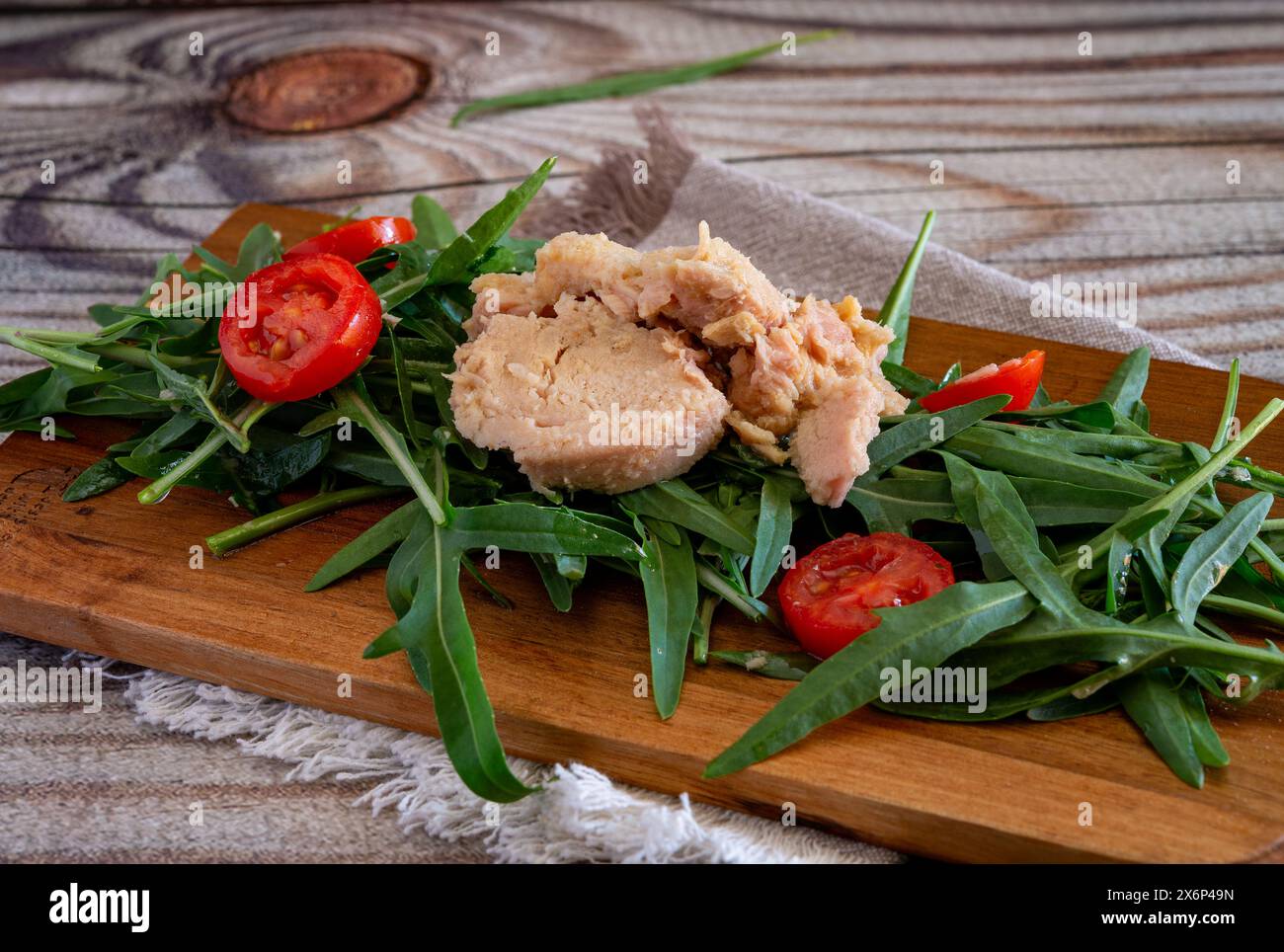 Leichte Vorspeise mit Rakete, Thunfisch und roten Kirschtomaten auf einem hölzernen Schneidebrett Stockfoto