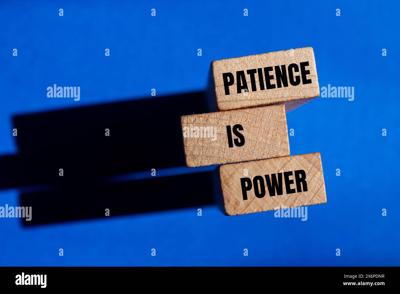 Geduld ist ein Schlagwort auf Holzblöcken mit blauem Hintergrund. Konzeptionelle Geduld ist ein Machtsymbol. Kopierbereich. Stockfoto