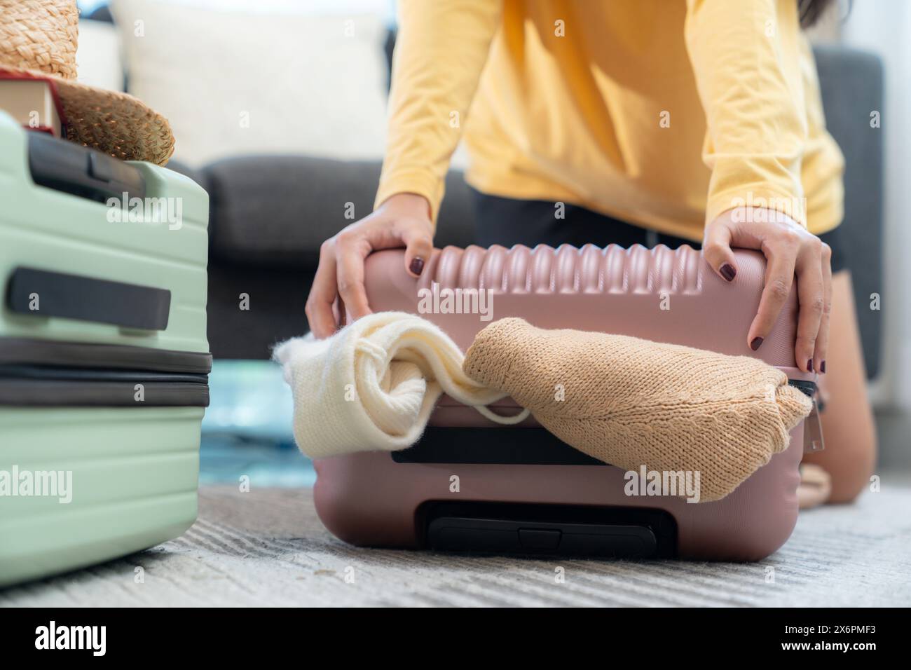 Eine junge Frau packt ihre Kleider und bereitet sich auf eine Reise vor Stockfoto