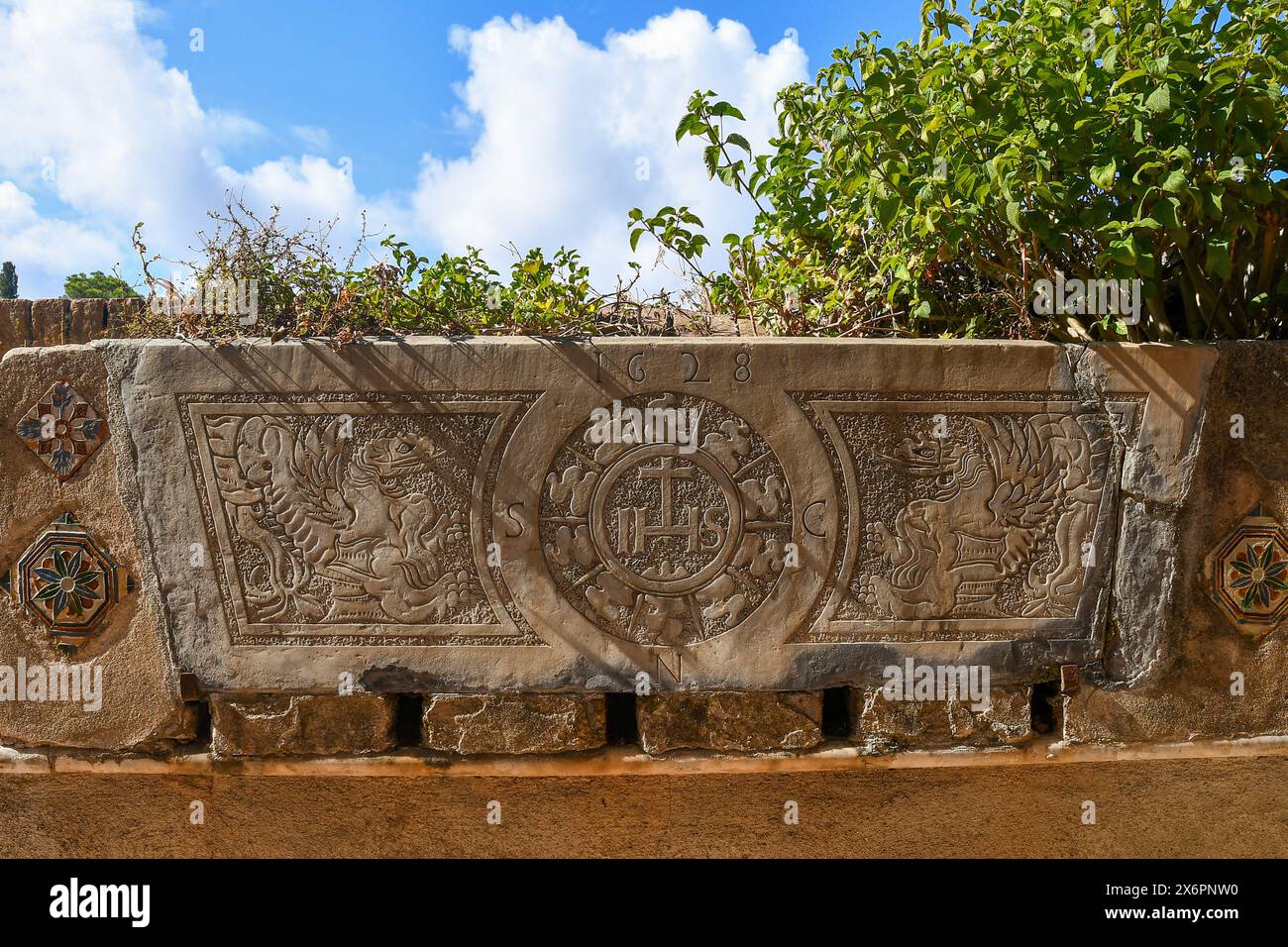 Stein aus dem Jahr 1628 mit einer Gravur, die ein Paar Greifer an den Seiten des Christus-Monogramms IHS im Garten des Brown Castle in Portofino darstellt Stockfoto