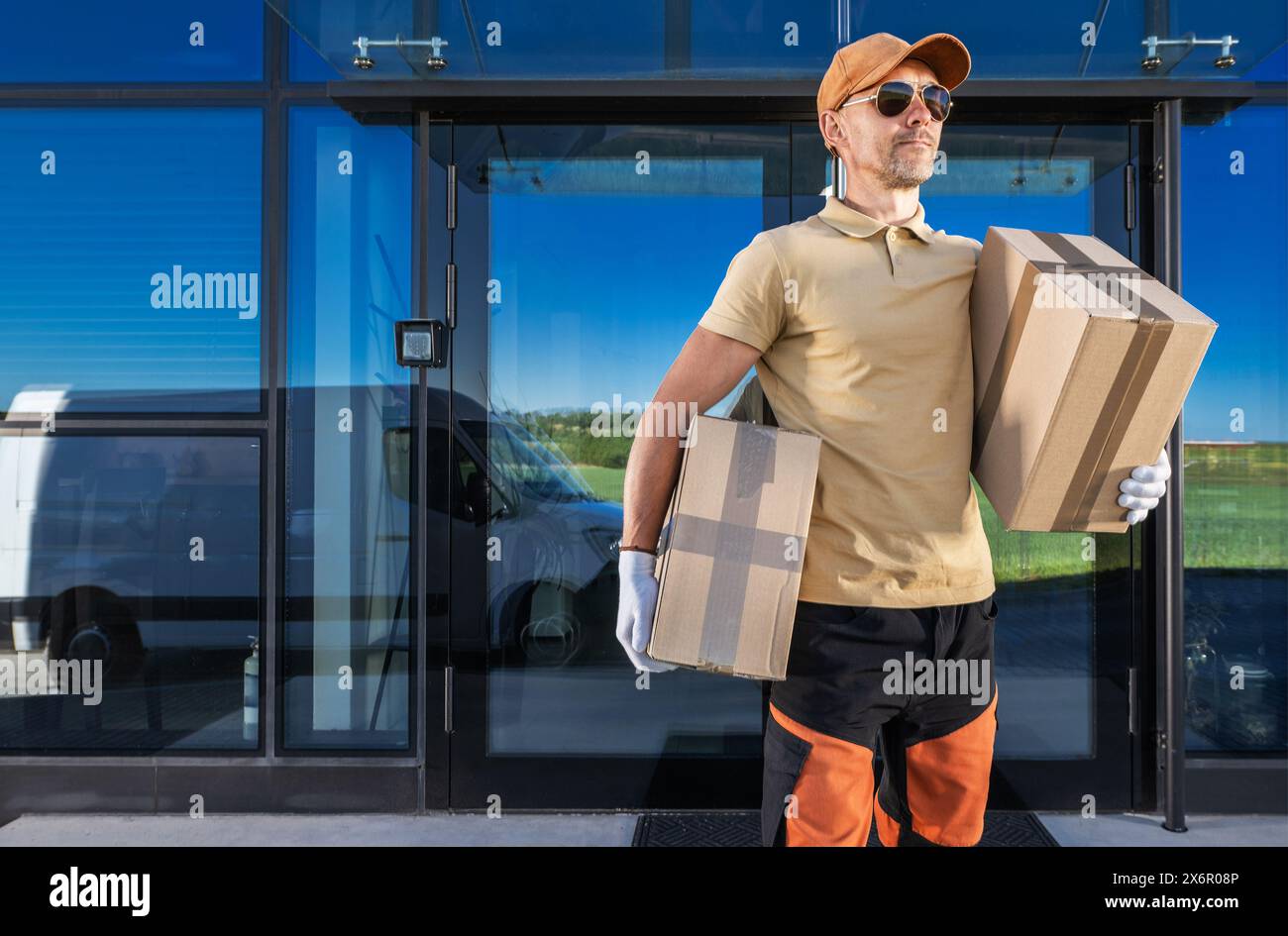 Ein Liefermann, der Kisten vor einem Gebäude trägt. Stockfoto