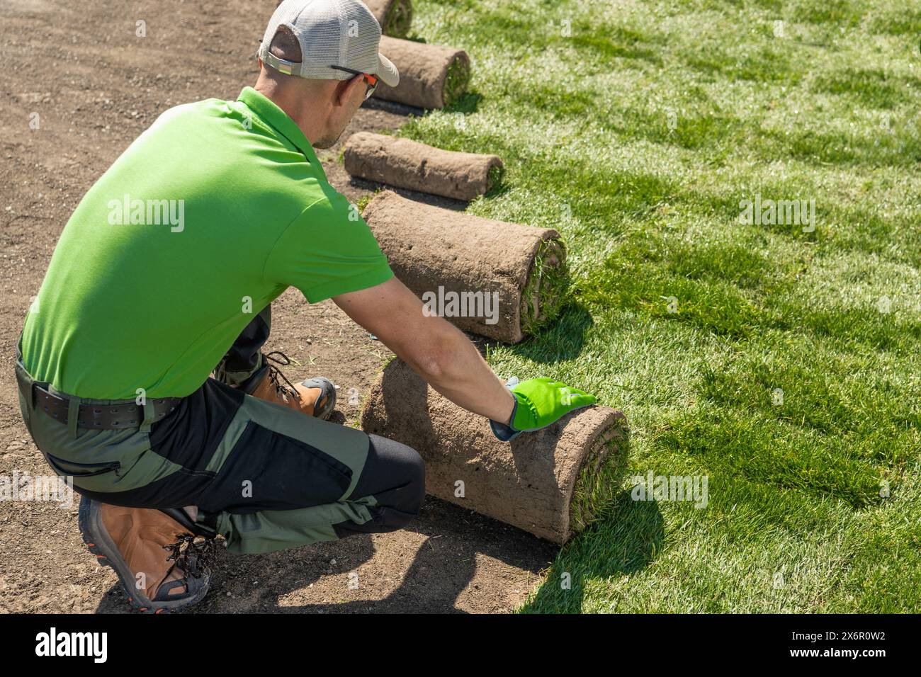 Der Gärtner legt vorsichtig Gras auf einem Rasen ab. Installation Von Grasrasen. Stockfoto