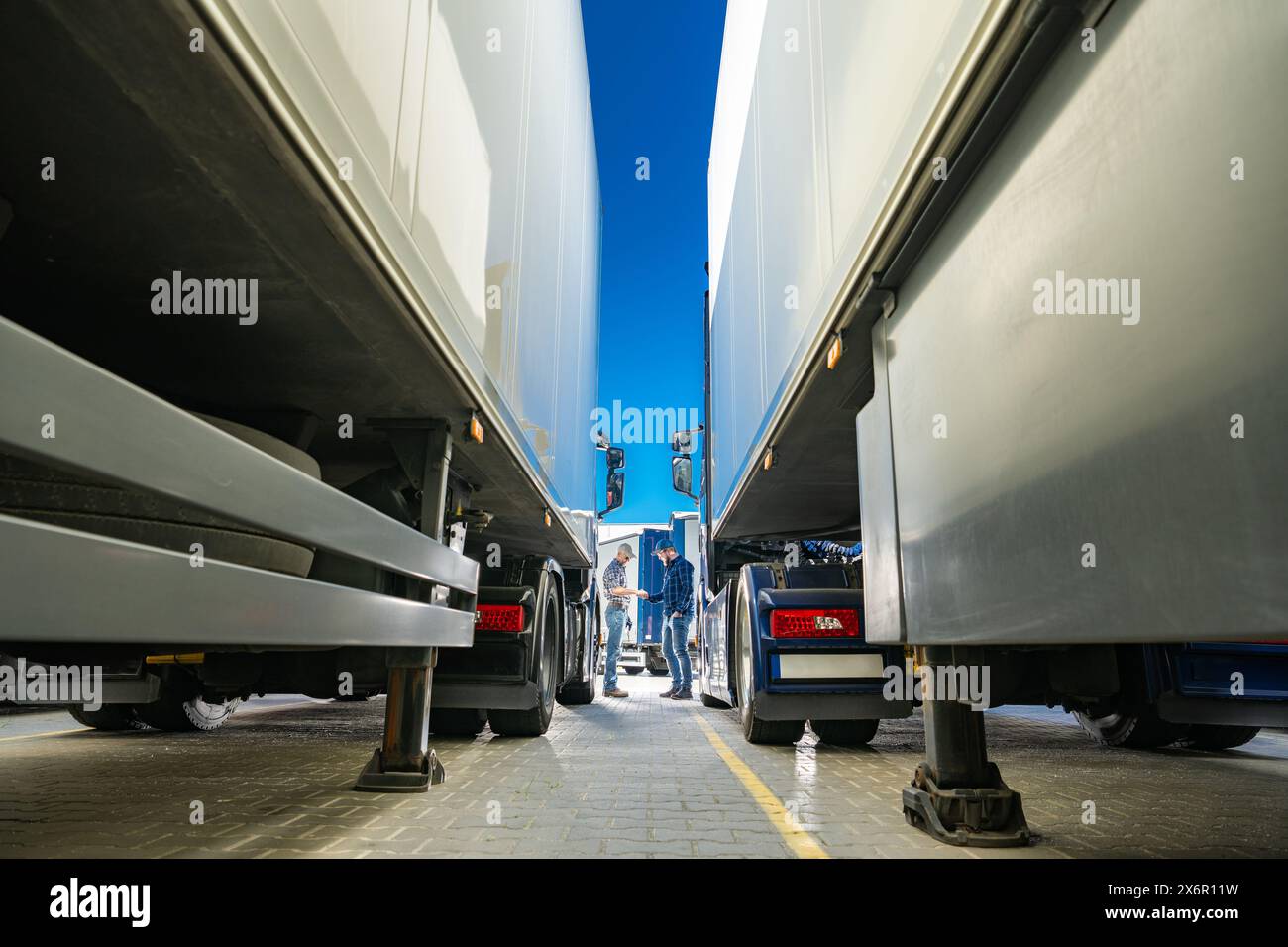 Eine Fuhrpark auf einem offenen Parkplatz und zwei kaukasische Fahrer treffen sich Stockfoto