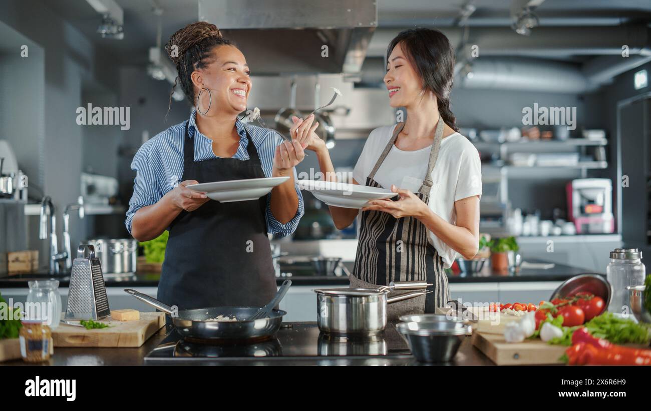 TV-Kochshow Küche mit zwei Meisterköchen. Asiatische und schwarze weibliche Moderatoren sprechen. Profis unterrichten, wie man Essen kocht und köstliches Gericht schmeckt. Online-Videokurse. Gesundes Gericht Rezept Vorbereiten Stockfoto