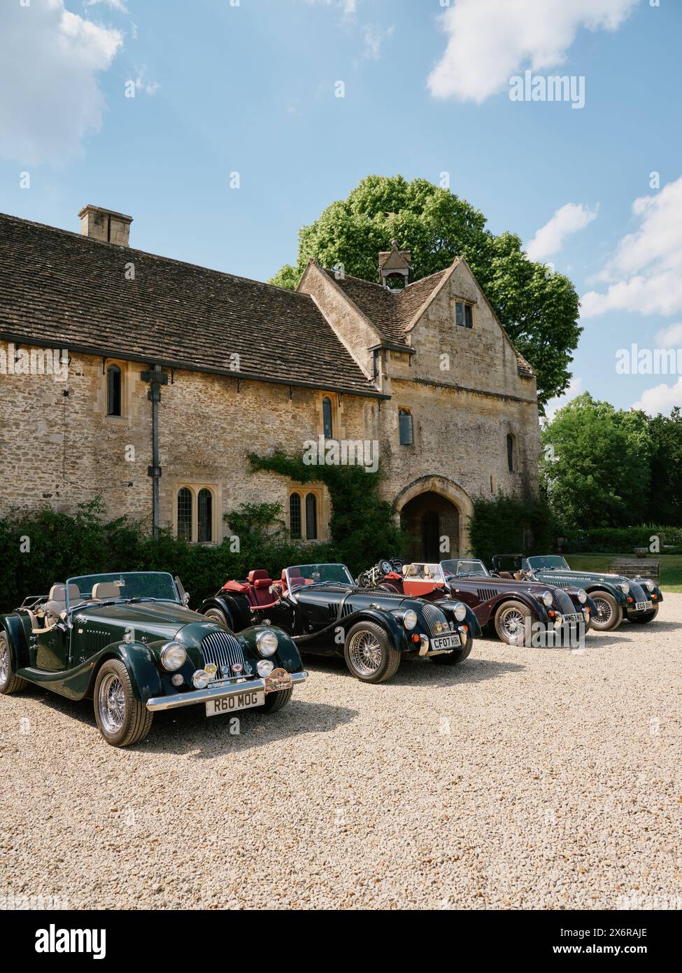 Die Autos des Morgan Sports Car Club standen alle vor einem traditionellen Haus in Wiltshire England, Großbritannien Stockfoto