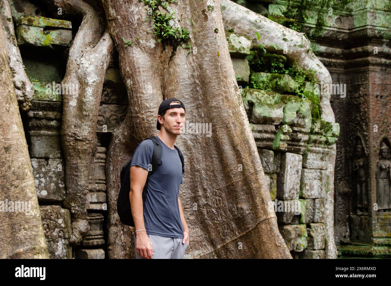 Kaukasischer Tourist vor dem Großen Stamm und Wurzeln eines Riesenbaums in Ta Prohm, Angkor Wat, Siem Reap, Kambodscha Stockfoto