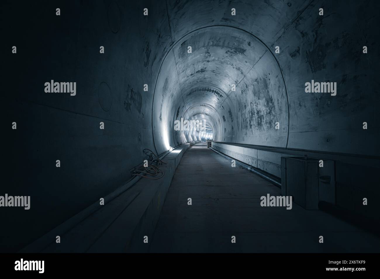 Ein leerer Tunnel mit Betonwänden und Lichtquellen an den Seiten, der eine dunkle, geheimnisvolle Atmosphäre hat, Tunnelbau Hermann Hesse Bahn Stockfoto