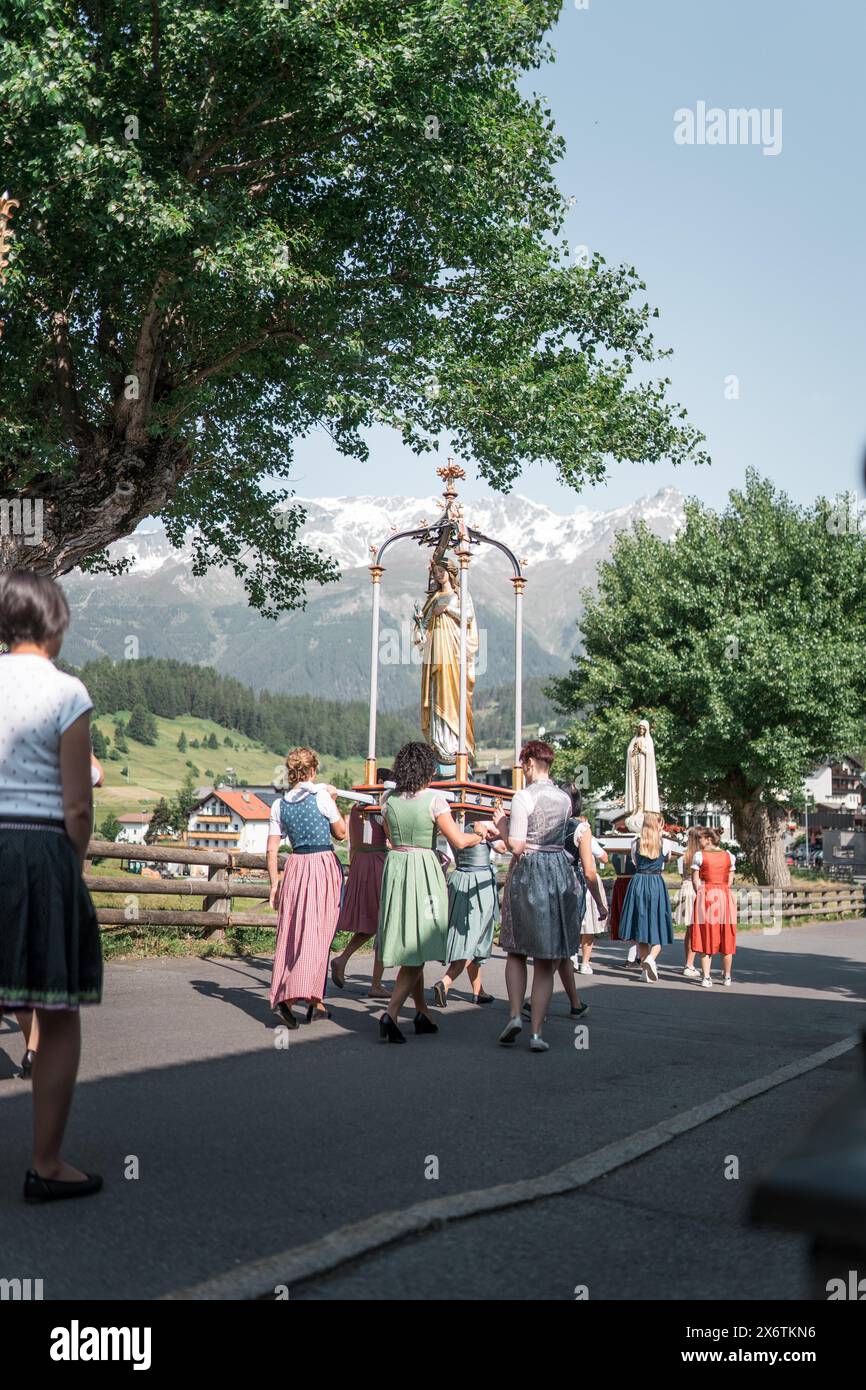 Eine Prozession mit einer Statue der Jungfrau Maria und traditionell gekleideten Menschen. Nauders, Österreich Stockfoto