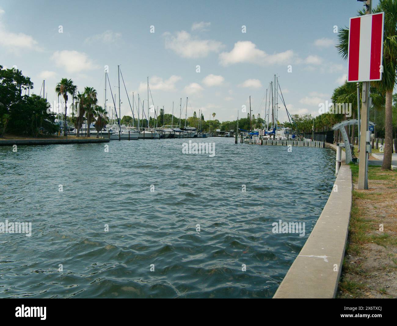 Weiter Blick nach Norden in die City of Gulfport Municipal Marina. Ruhiges blaues Wasser mit einem kleinen Boot. Wellige Wellen. Bootsanlegestelle, Holzpfähle und Boote Stockfoto