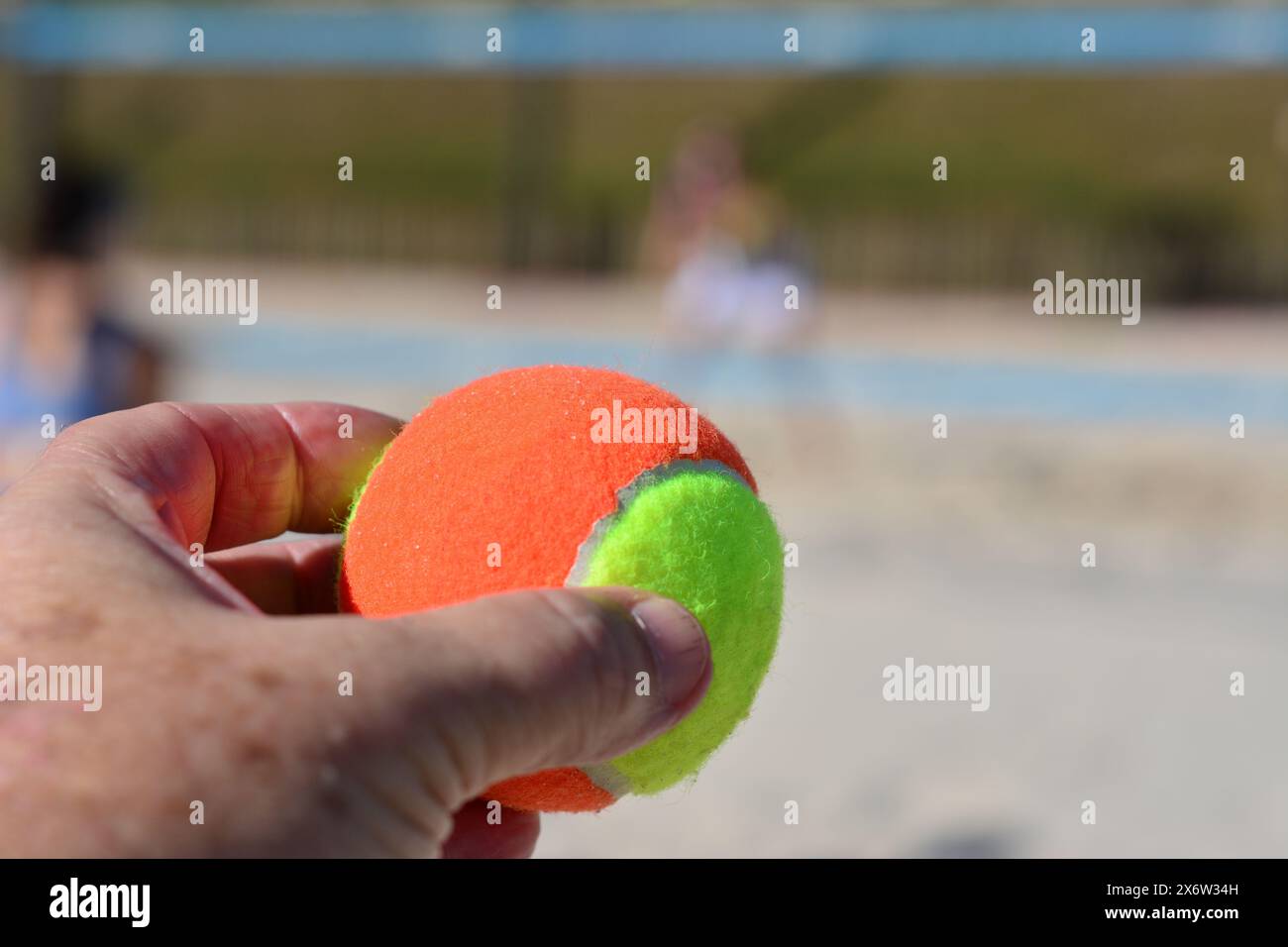 Gelber Tennisball mit Logo auf dem Ball selbst in den Händen eines Trainers Stockfoto