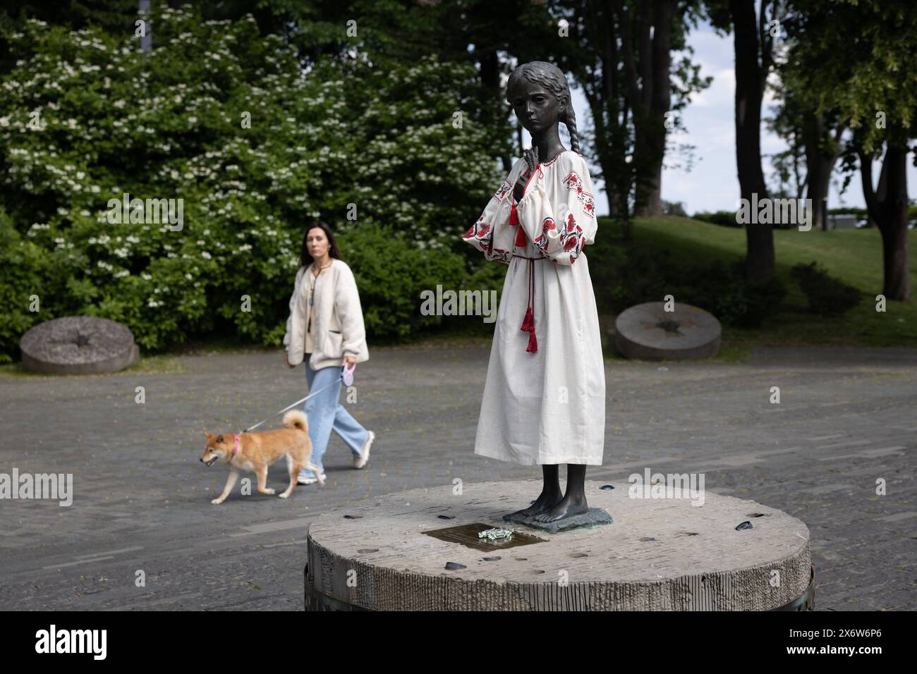 Ein Mädchen spaziert in der Nähe des Denkmals „bittere Erinnerung an die Kindheit“, das die Opfer des Holodomor (Hungersnot) symbolisiert, das in besticktem Hemd anlässlich des Vyshyvanka-Tages in Kiew gekleidet ist. Stockfoto