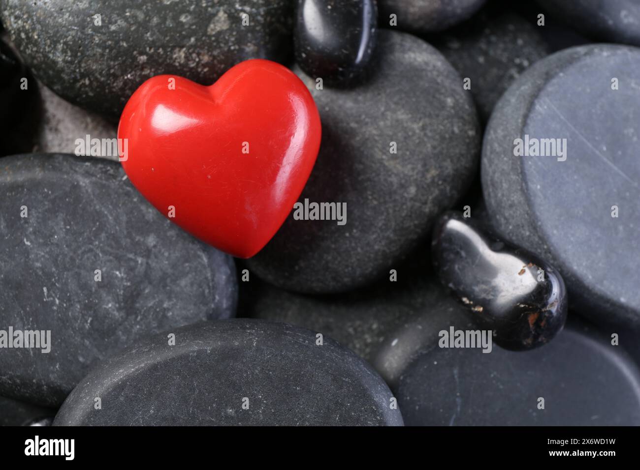 Rotes dekoratives Herz auf Kieselsteinen, Ansicht oben Stockfoto