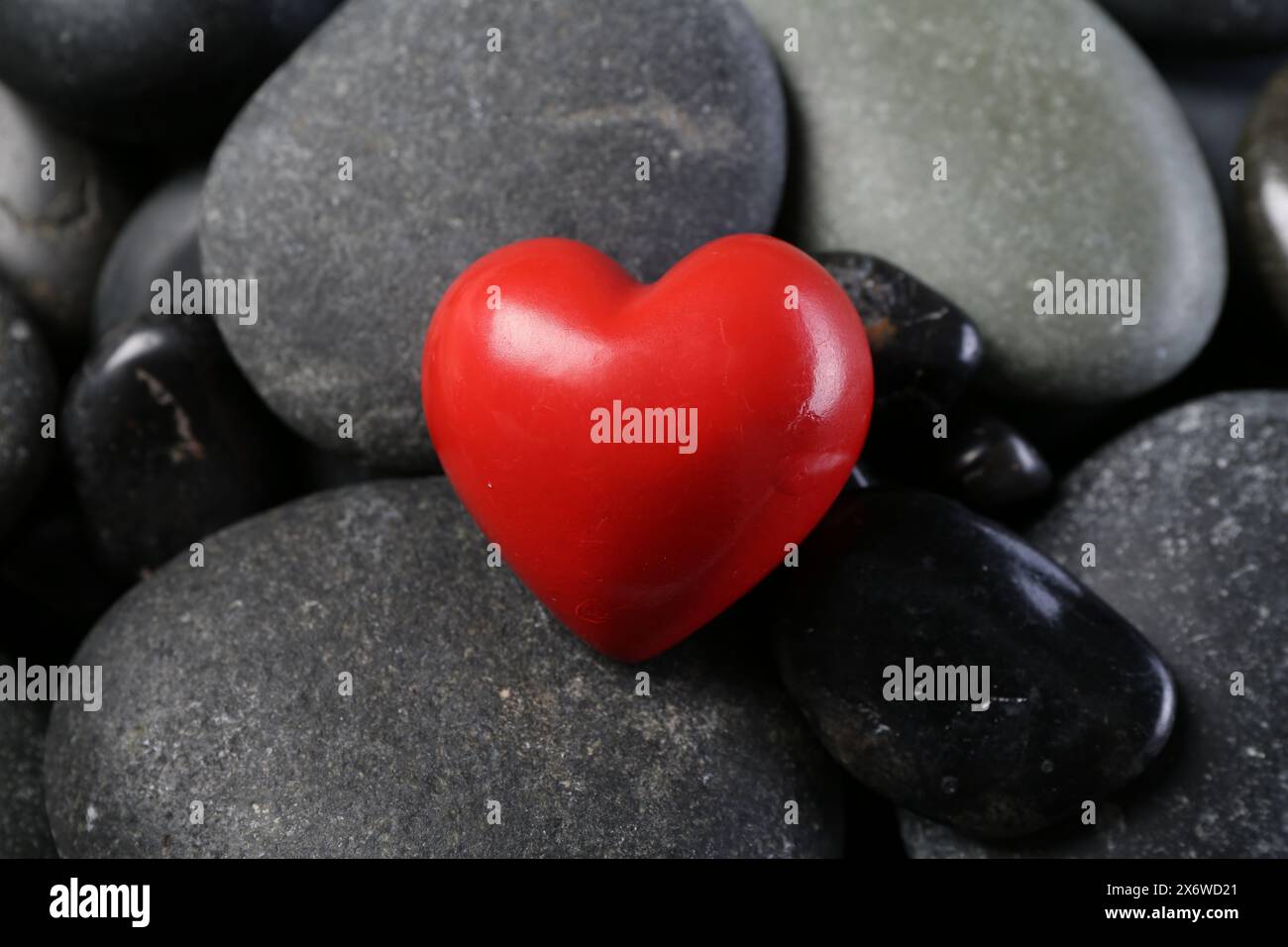 Rotes dekoratives Herz auf Kieselsteinen, Nahaufnahme Stockfoto