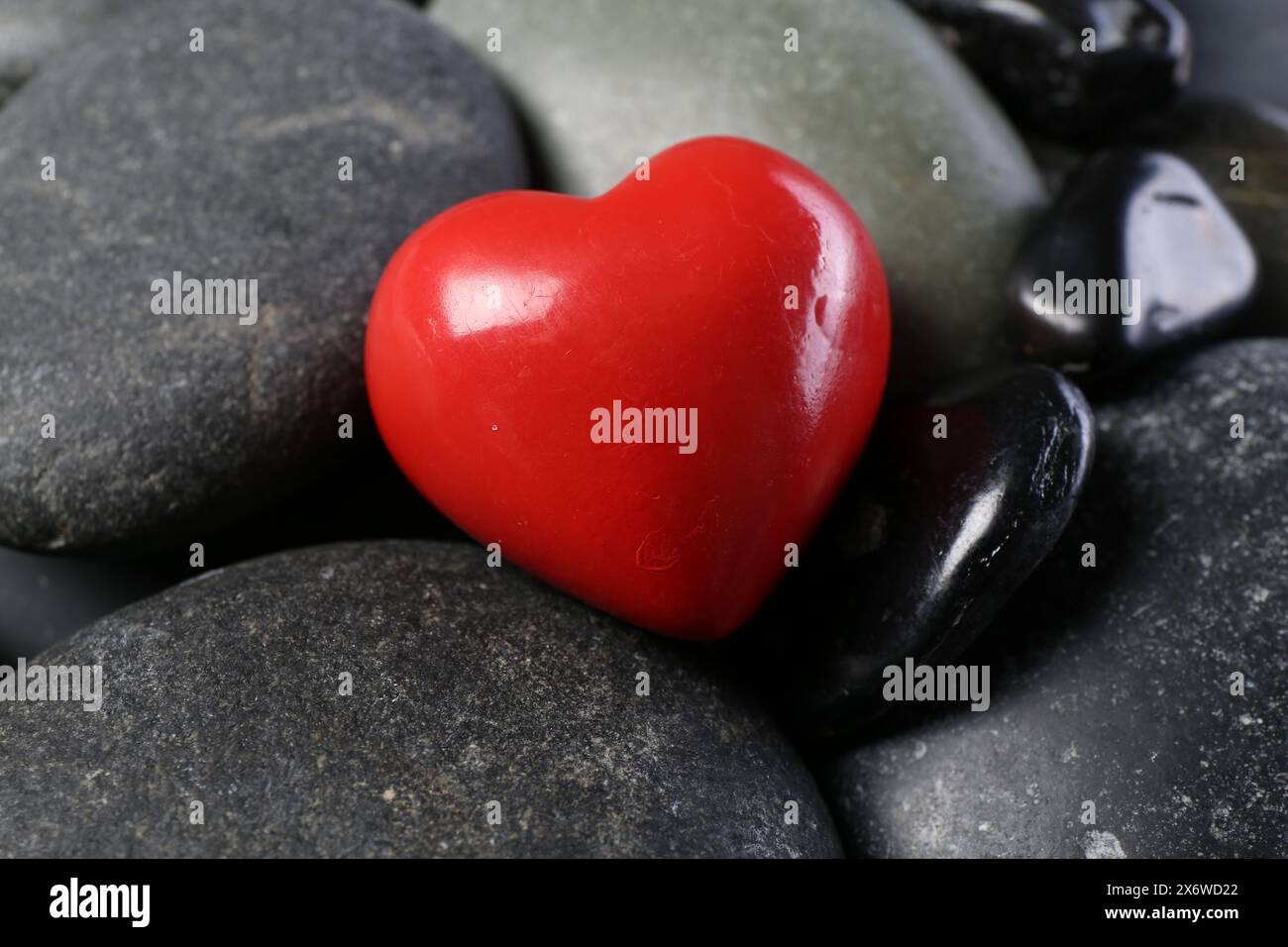 Rotes dekoratives Herz auf Kieselsteinen, Nahaufnahme Stockfoto