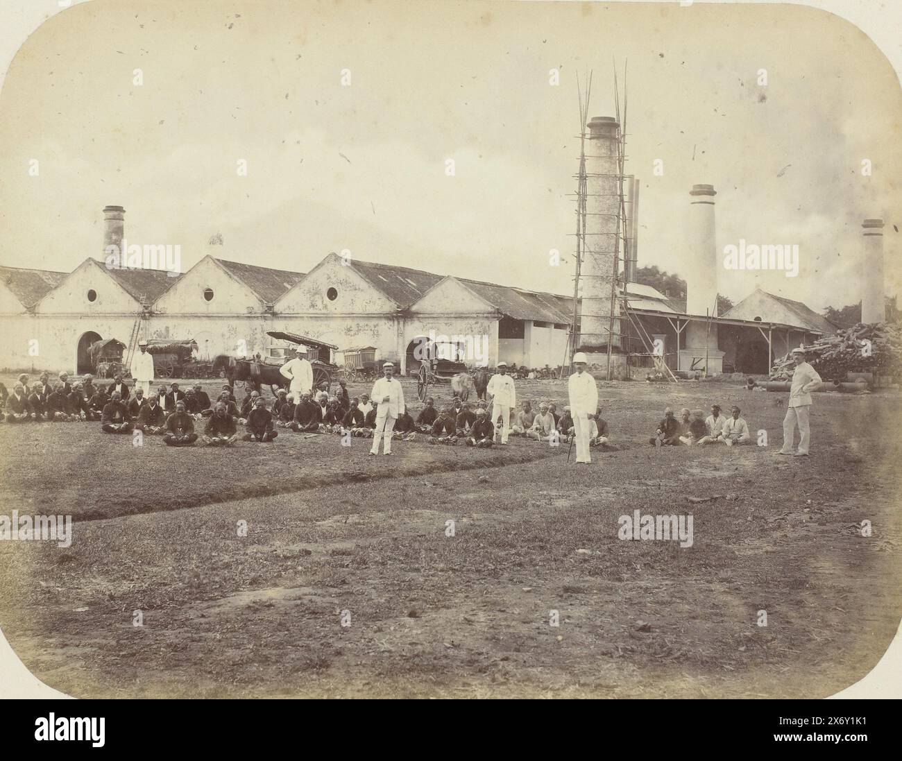 Eine Zuckerfabrik, Eine Zuckerfabrik mit sechs Schornsteinen, von denen einer im Gerüst ist. Im Vordergrund ein Rasen mit stehenden Europäern und sitzenden javanischen Arbeitern. Teil des Fotoalbums, das von der Soerabayasche Association of Suikerfabrikanten an Frederik Beyerinck, Einwohner von Soerabaya, präsentiert wurde., Foto, Herman Salzwedel, Soerabayasche Vereeniging van Suikerfabrikanten, Surabaya, 1876 - 1884, fotografische Unterstützung, Albumendruck, Höhe, 21,8 cm x Breite, 28,4 cm Stockfoto